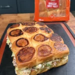 Toasted King's Hawaiian sweet roll sliders filled with chopped cheeseburger mixture on a slate board