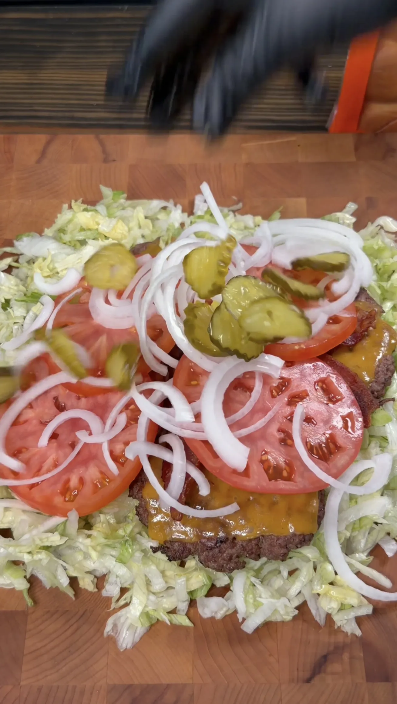 Chopped cheeseburger toppings of tomato, onion, pickles, and lettuce piled with a cheesy patty