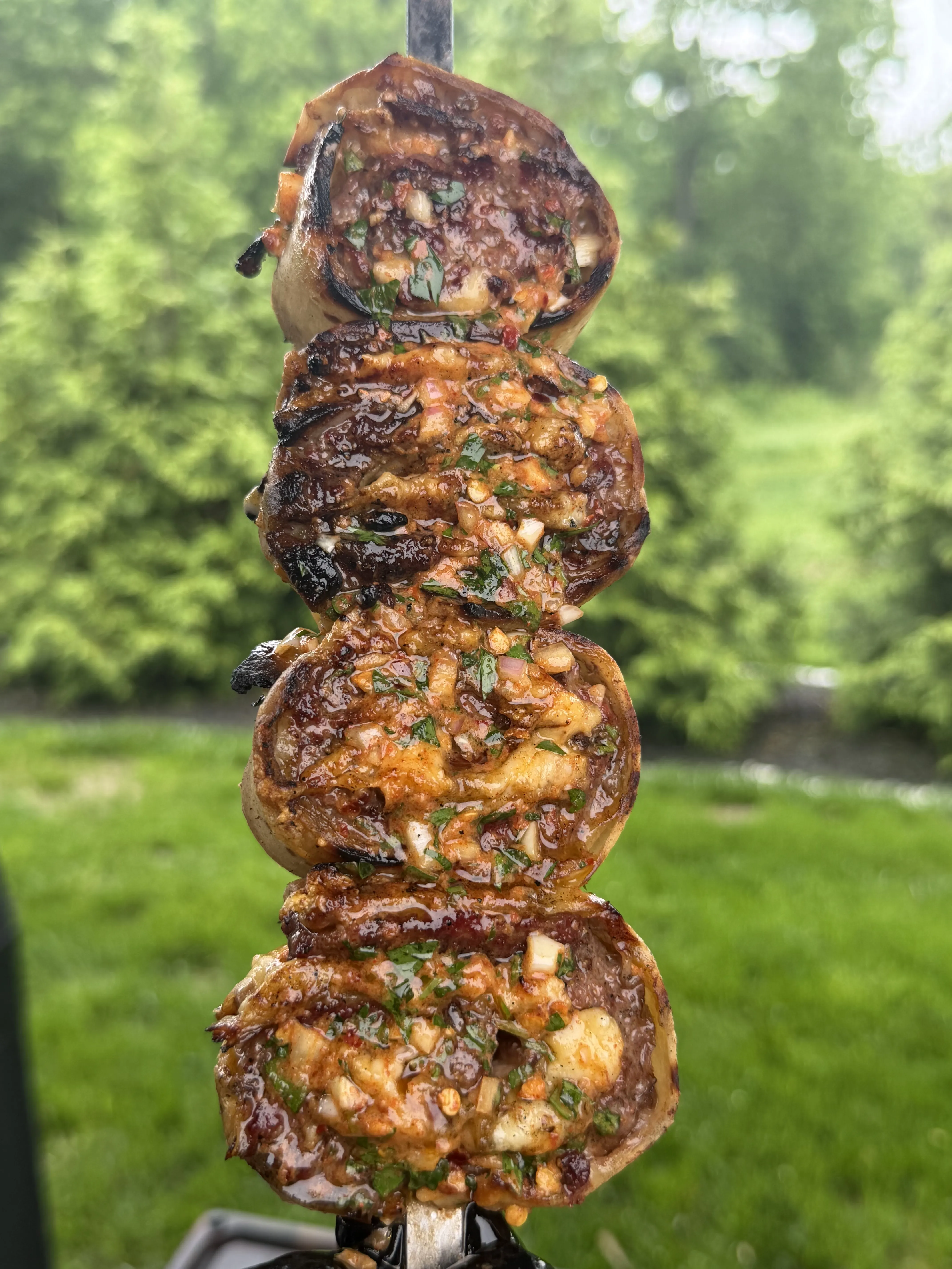 Finished grilled cowboy butter beef tortilla pinwheels on a skewer with herb butter glaze