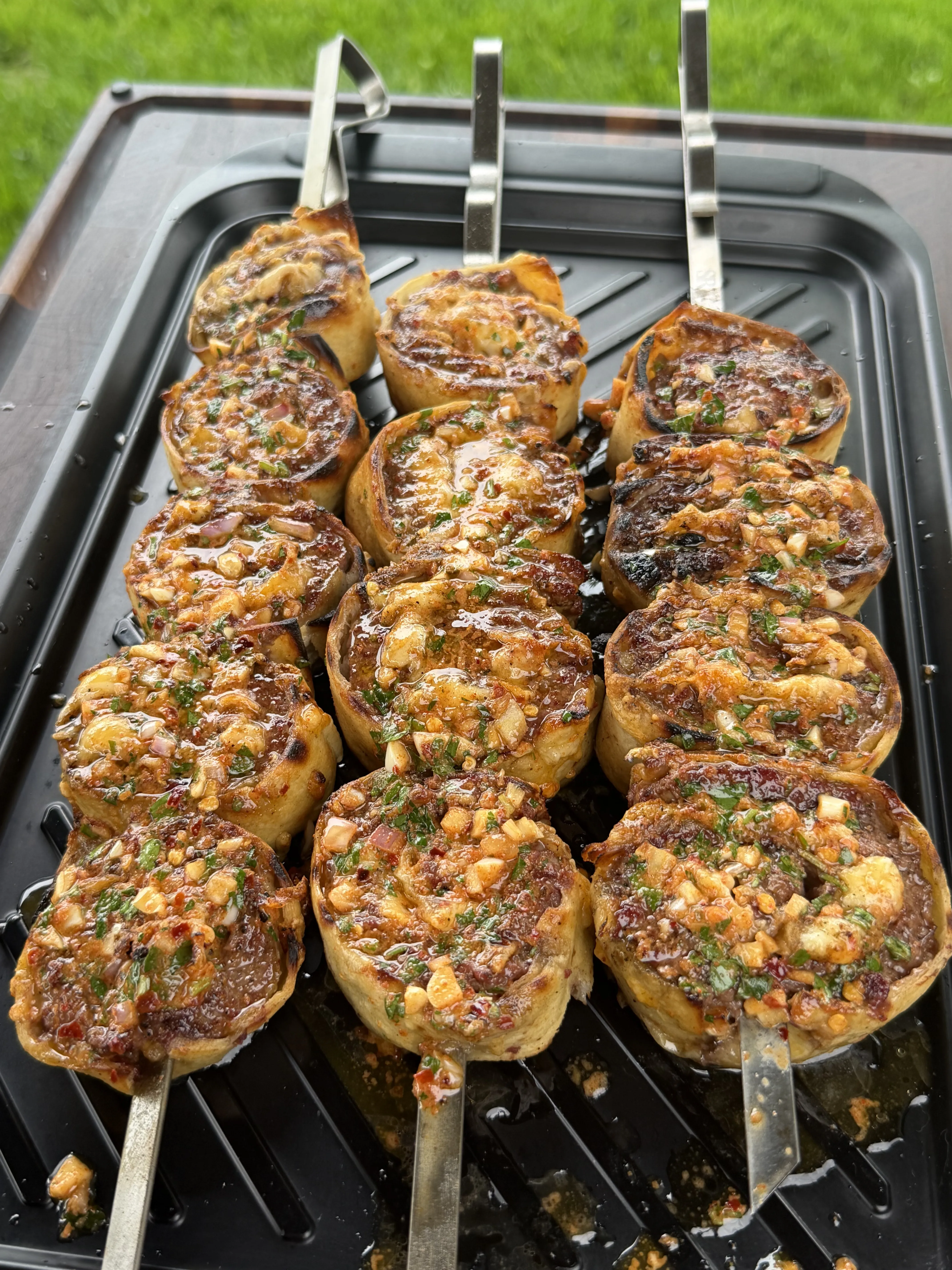 Grilled cowboy butter beef tortilla pinwheels topped with garlic, herbs, and chili flakes