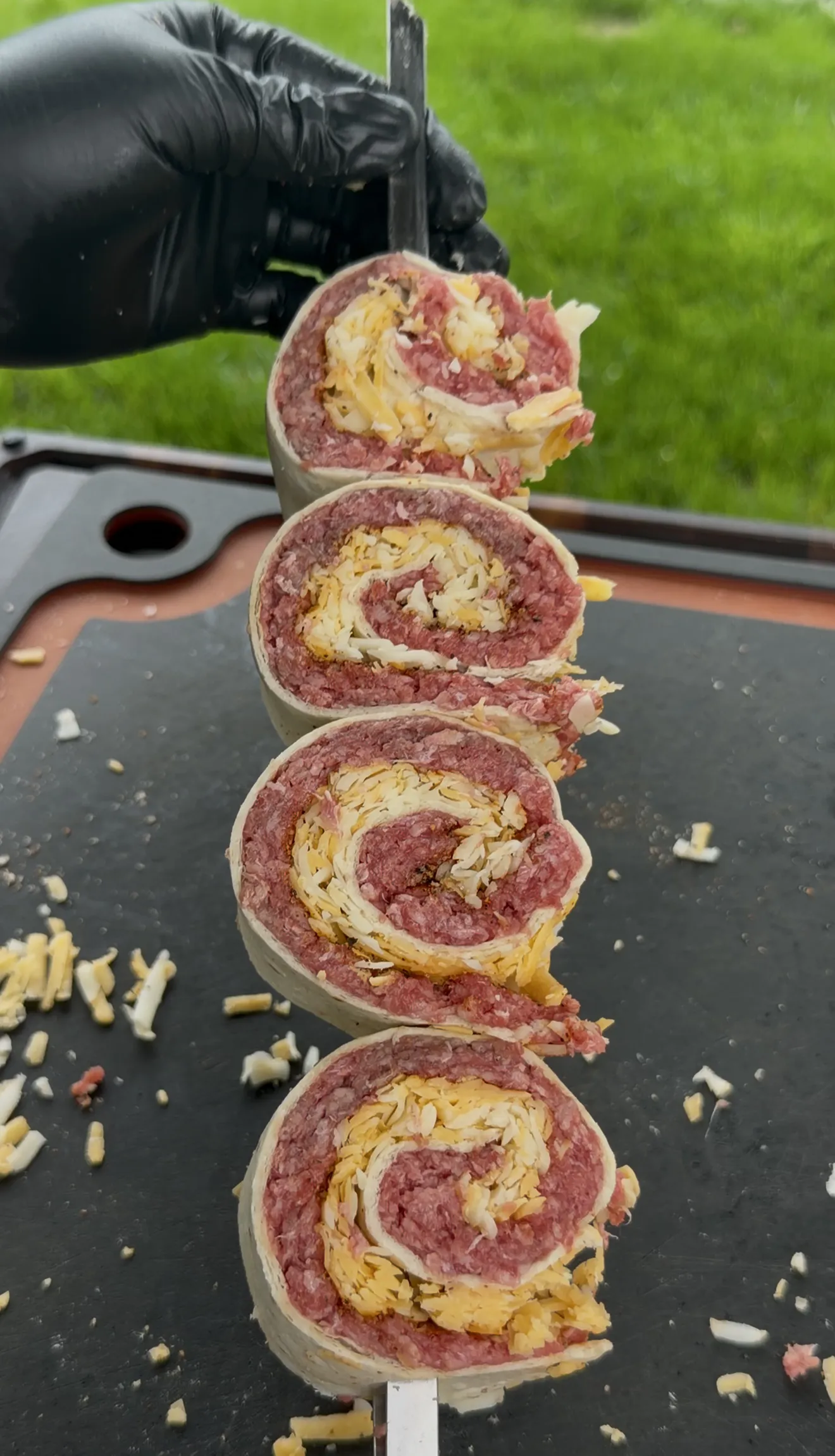 Raw beef and cheese tortilla pinwheels stacked on a skewer showing spiral cross-sections