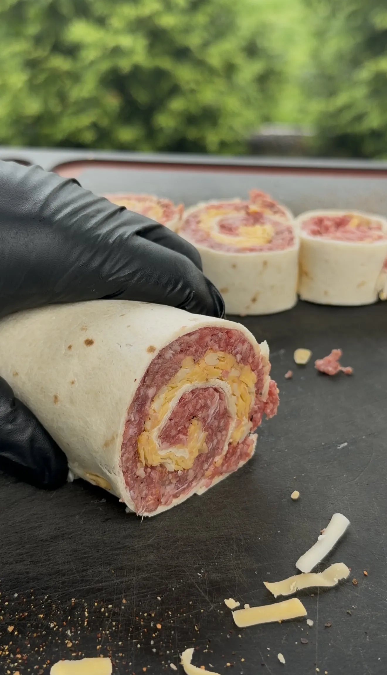 Sliced beef tortilla pinwheels showing spiral layers of ground beef and cheese on a dark cutting board