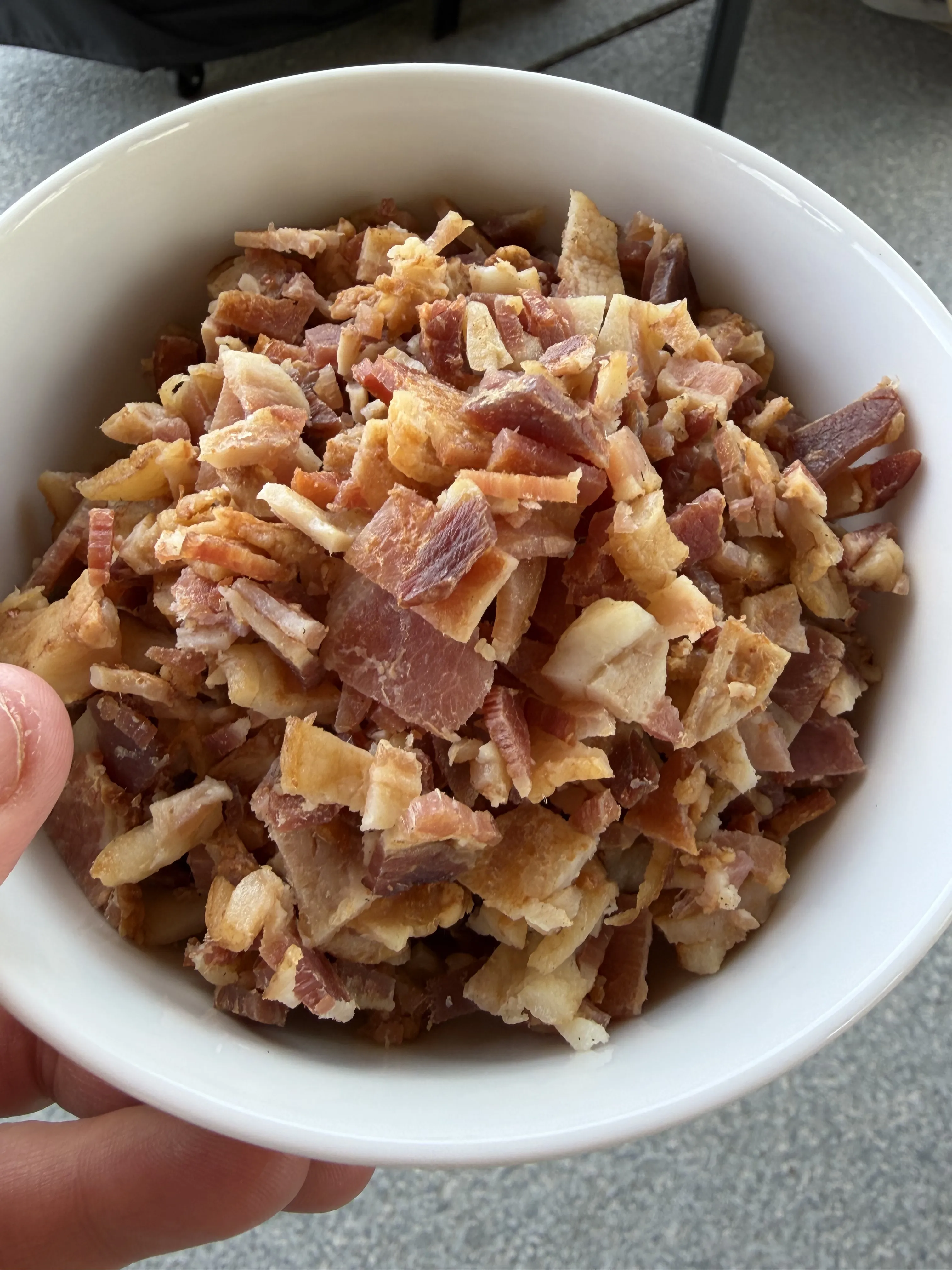 Chopped crispy bacon pieces in a white bowl ready for the beef pinwheel filling