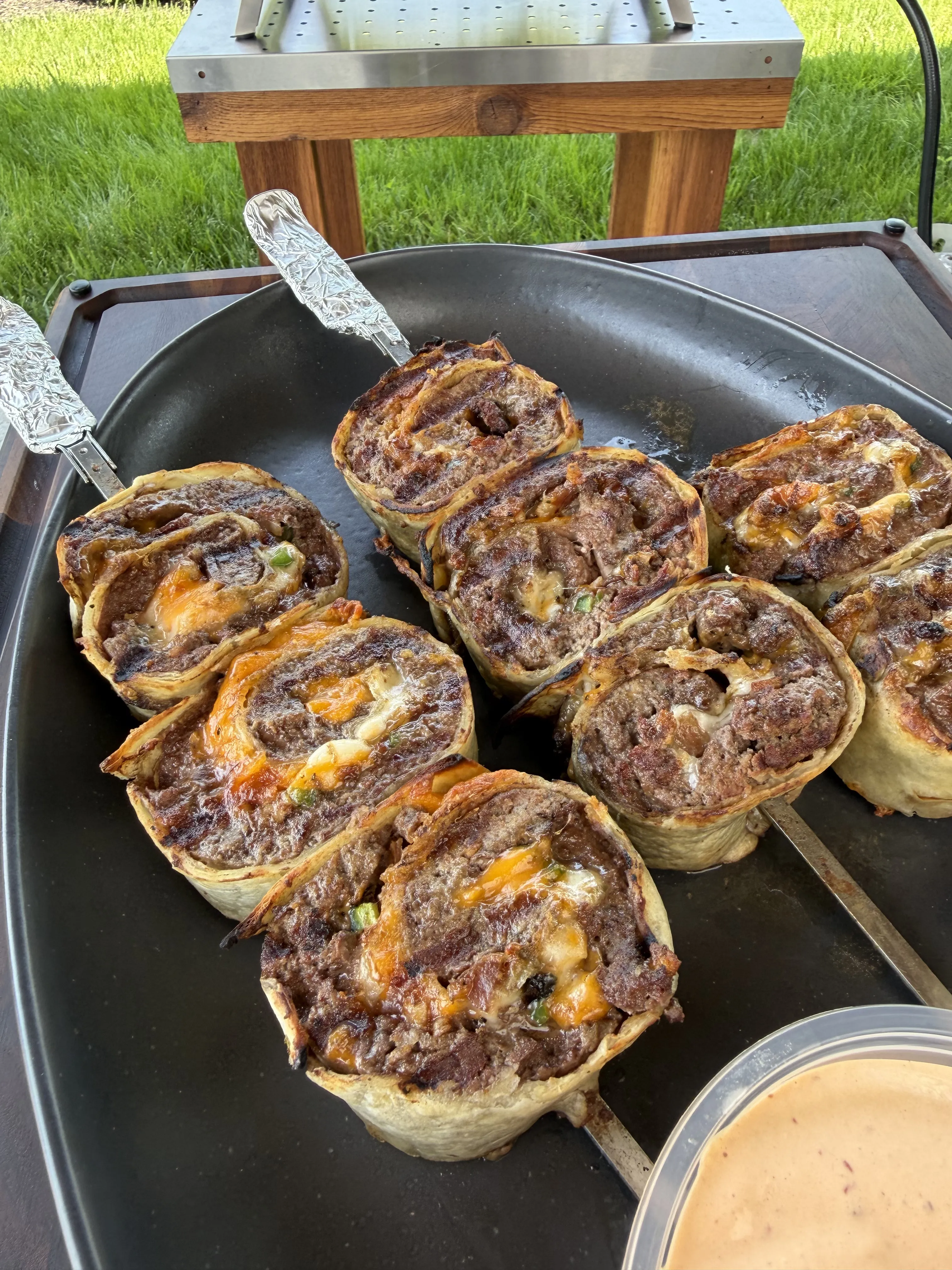 Crispy jalapeño bacon beef pinwheels cooking on a griddle with golden brown tortilla