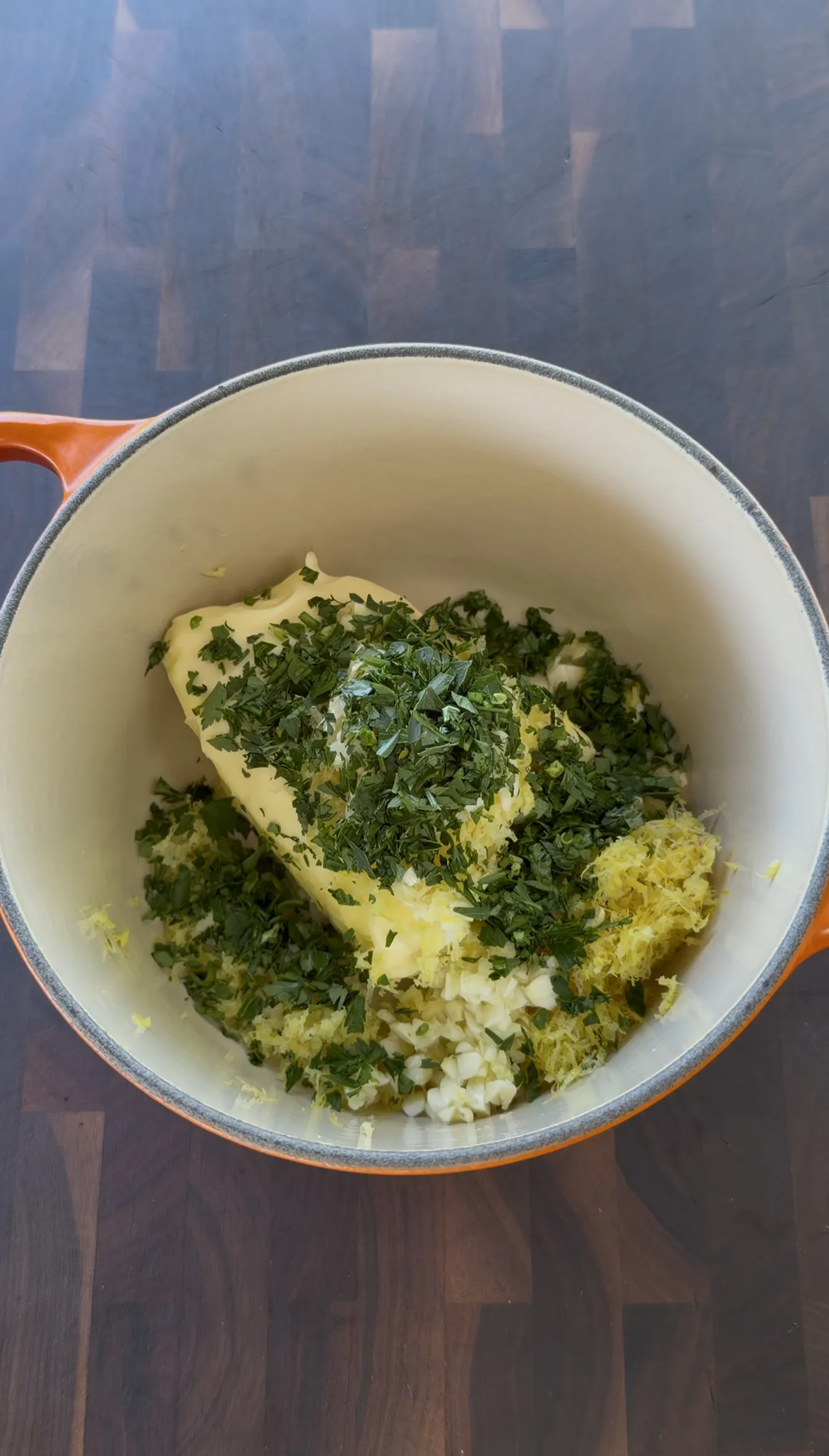 Fresh parsley, thyme, rosemary, minced garlic, and lemon zest in a mixing bowl for the compound butter