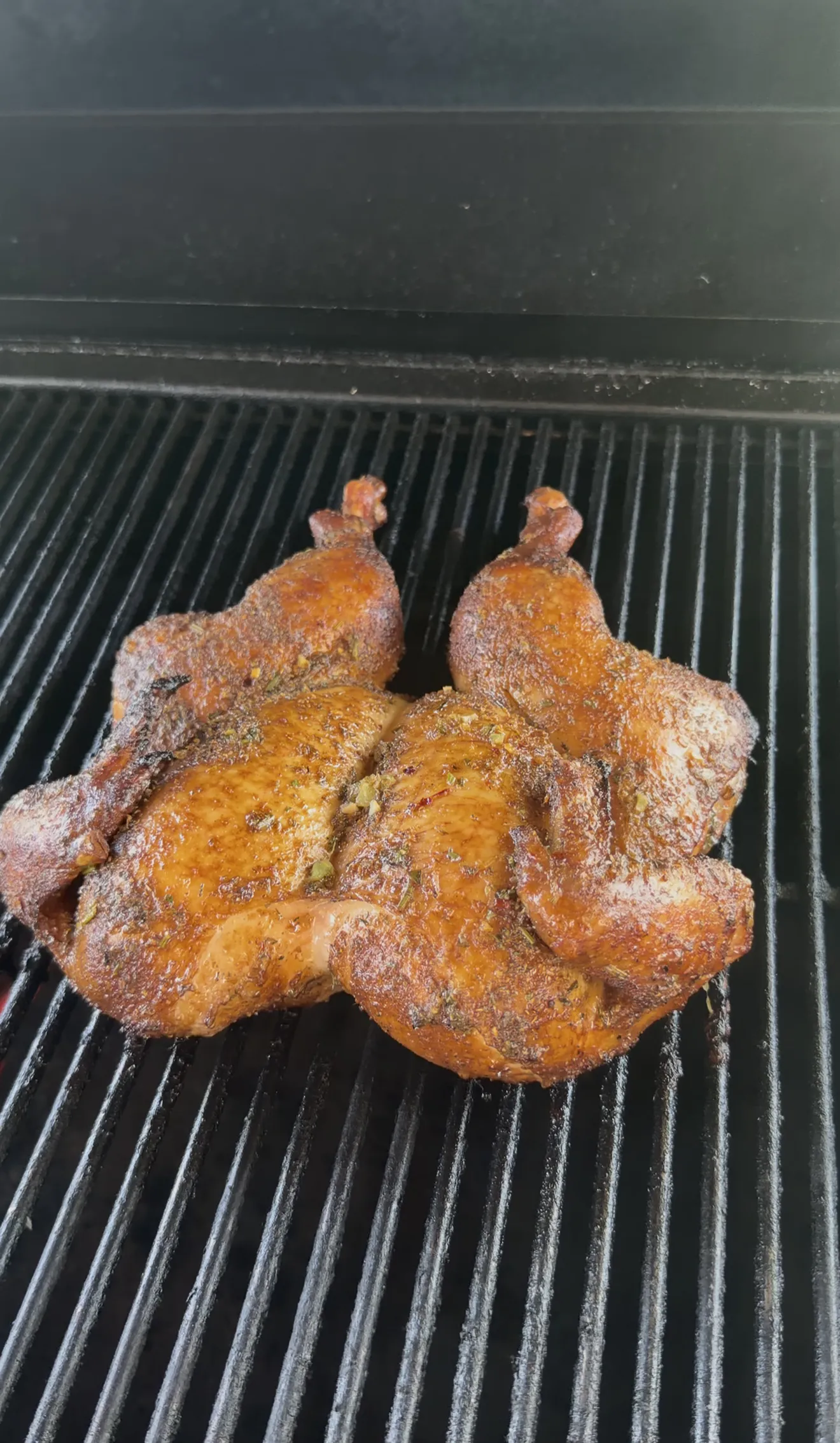Spatchcock chicken with crispy golden skin cooking on gas grill grates