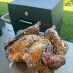 Golden brown whole lemon garlic chicken with crispy skin fresh off outdoor smoker grill
