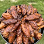 Hot honey lemon pepper chicken wings arranged in a black cast iron skillet, glazed and golden brown