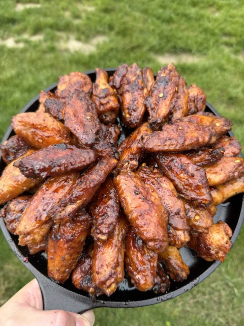 Hot honey lemon pepper chicken wings arranged in a black cast iron skillet, glazed and golden brown