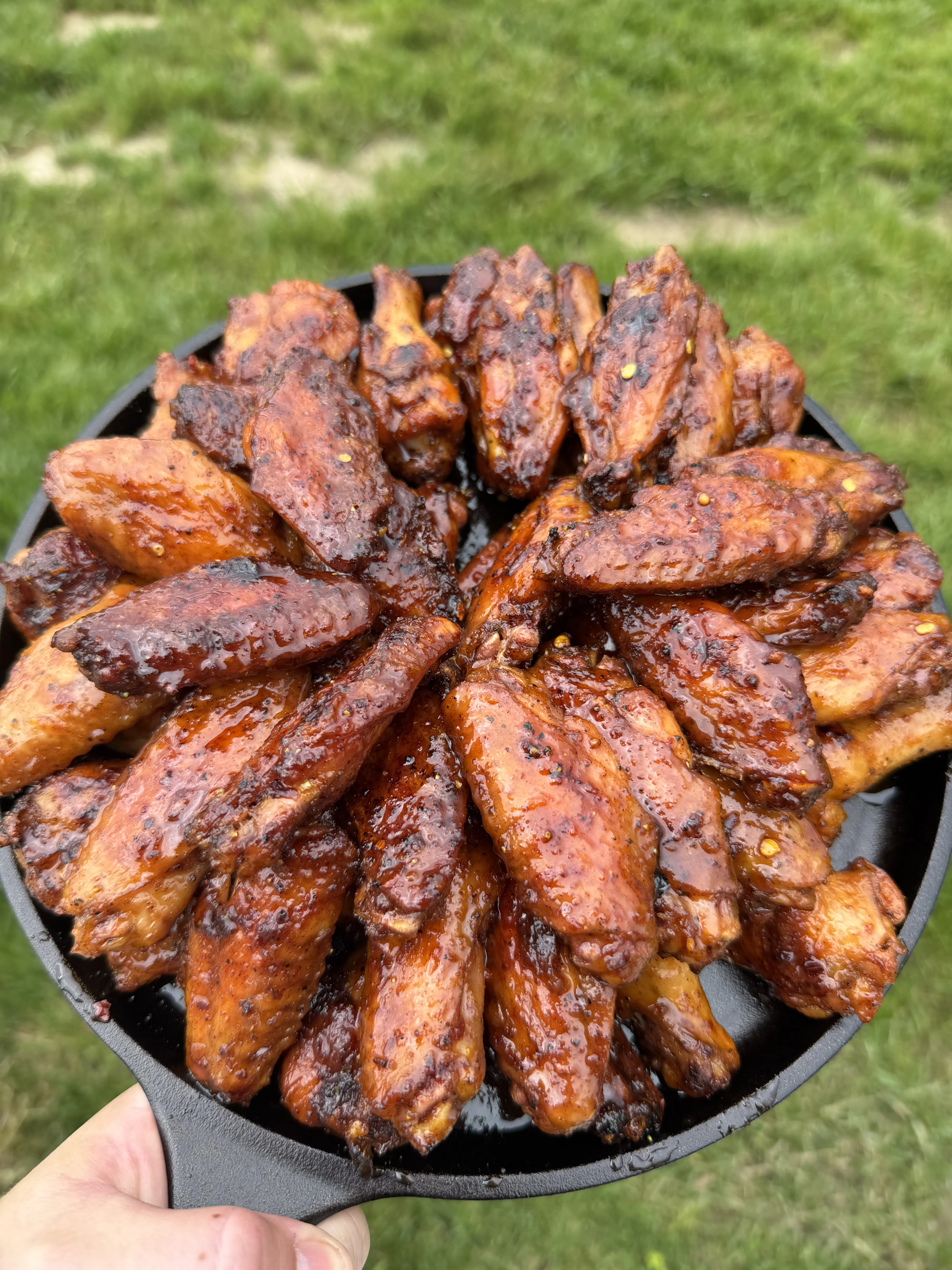 Hot honey lemon pepper wings glazed and golden brown in a cast iron skillet