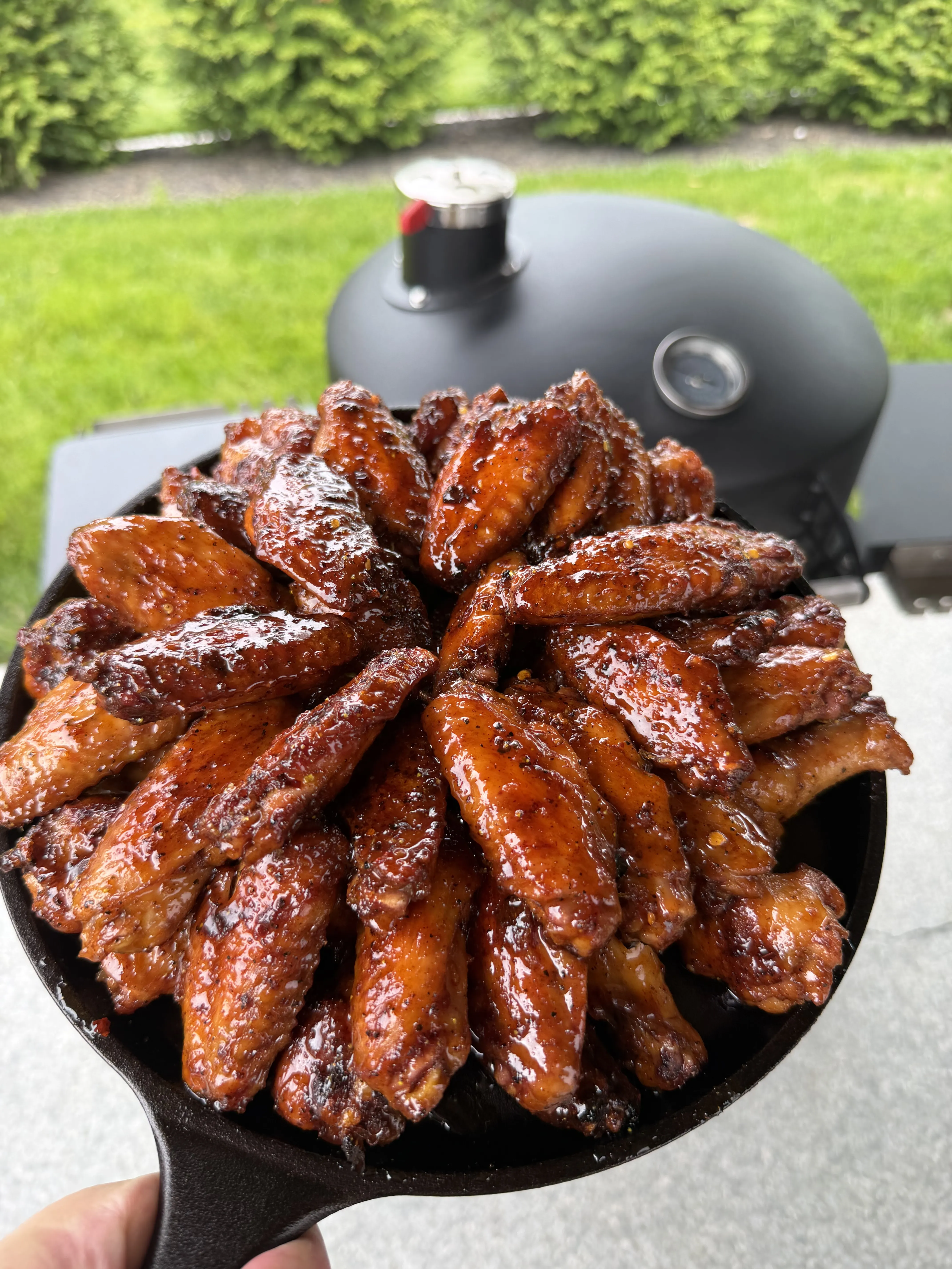 Glazed wings back on the grill in a cast iron skillet to set the sauce