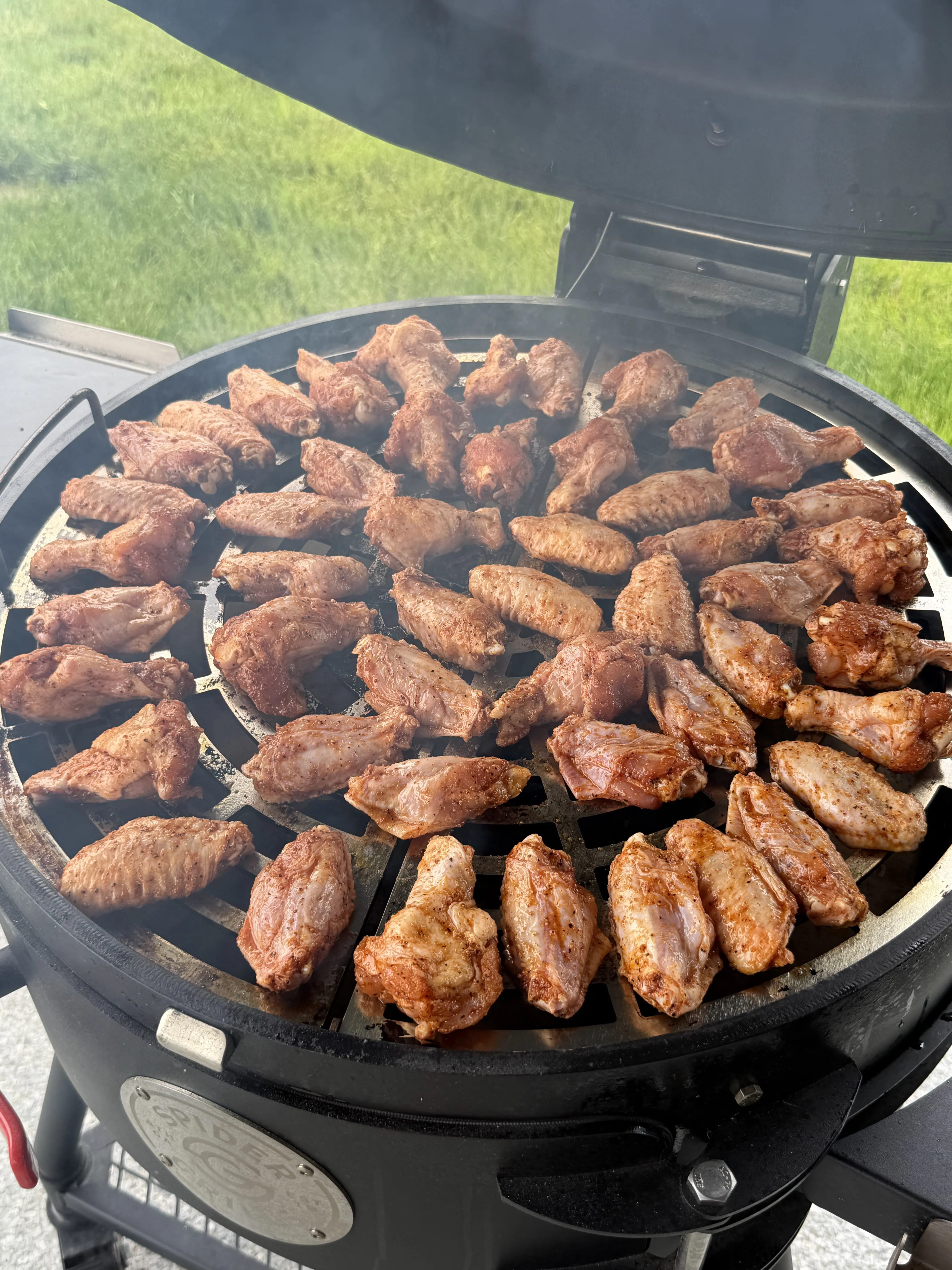 Lemon pepper wings cooking over indirect heat on a round charcoal grill