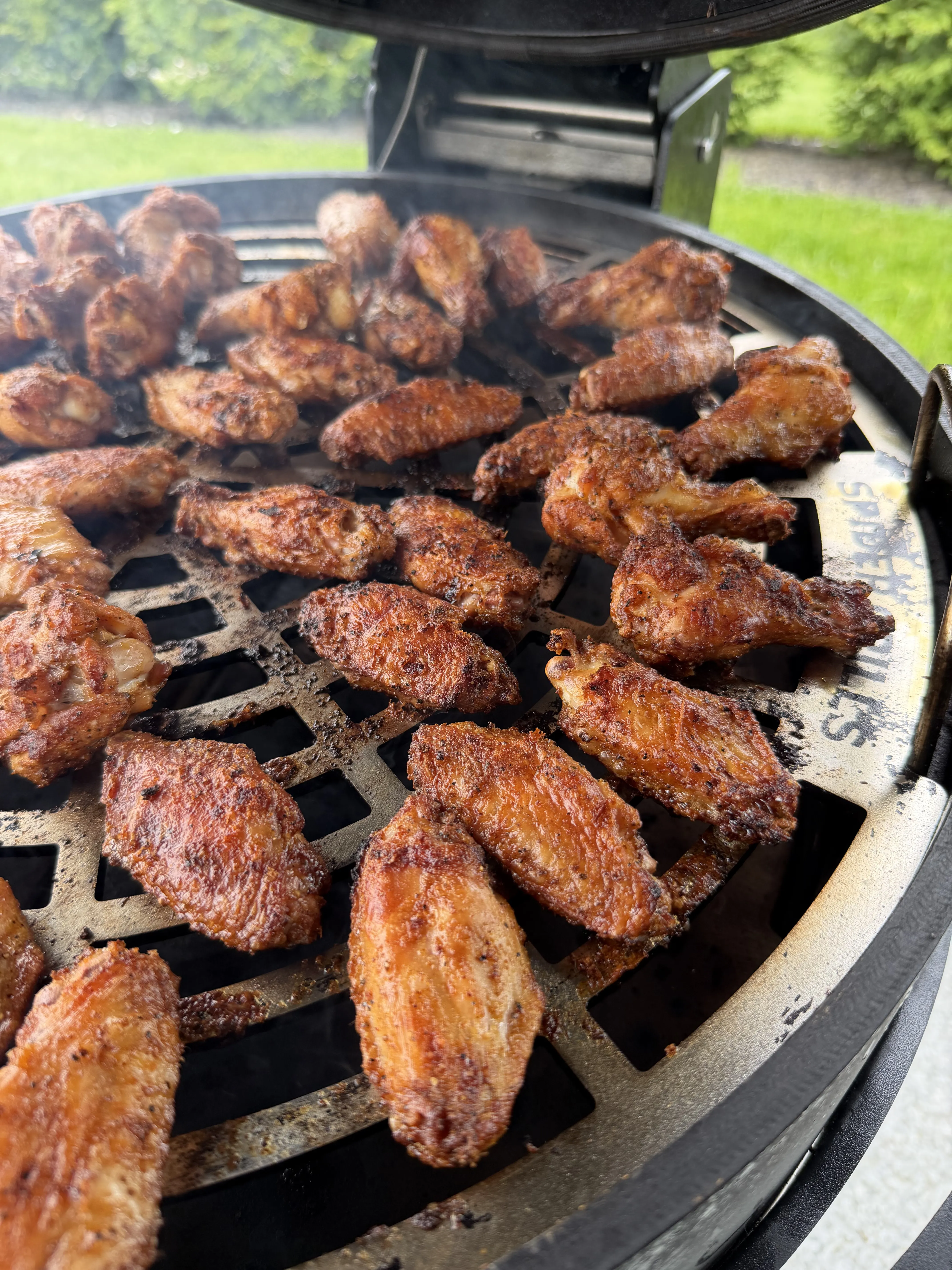 Hot honey lemon pepper chicken wings grilling on the BBQ grate with golden brown crispy skin