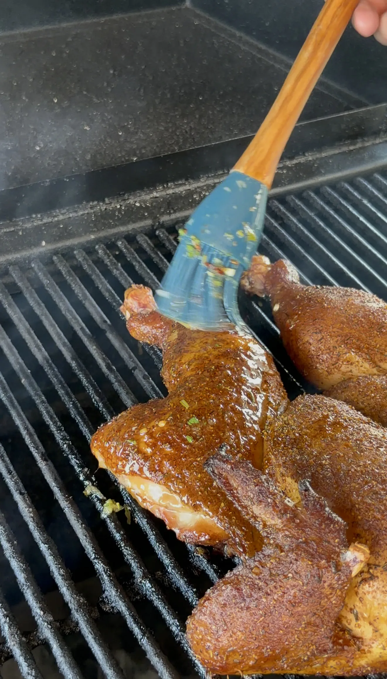 Final basting pass of melted herb butter on the spatchcock chicken before pulling from the grill