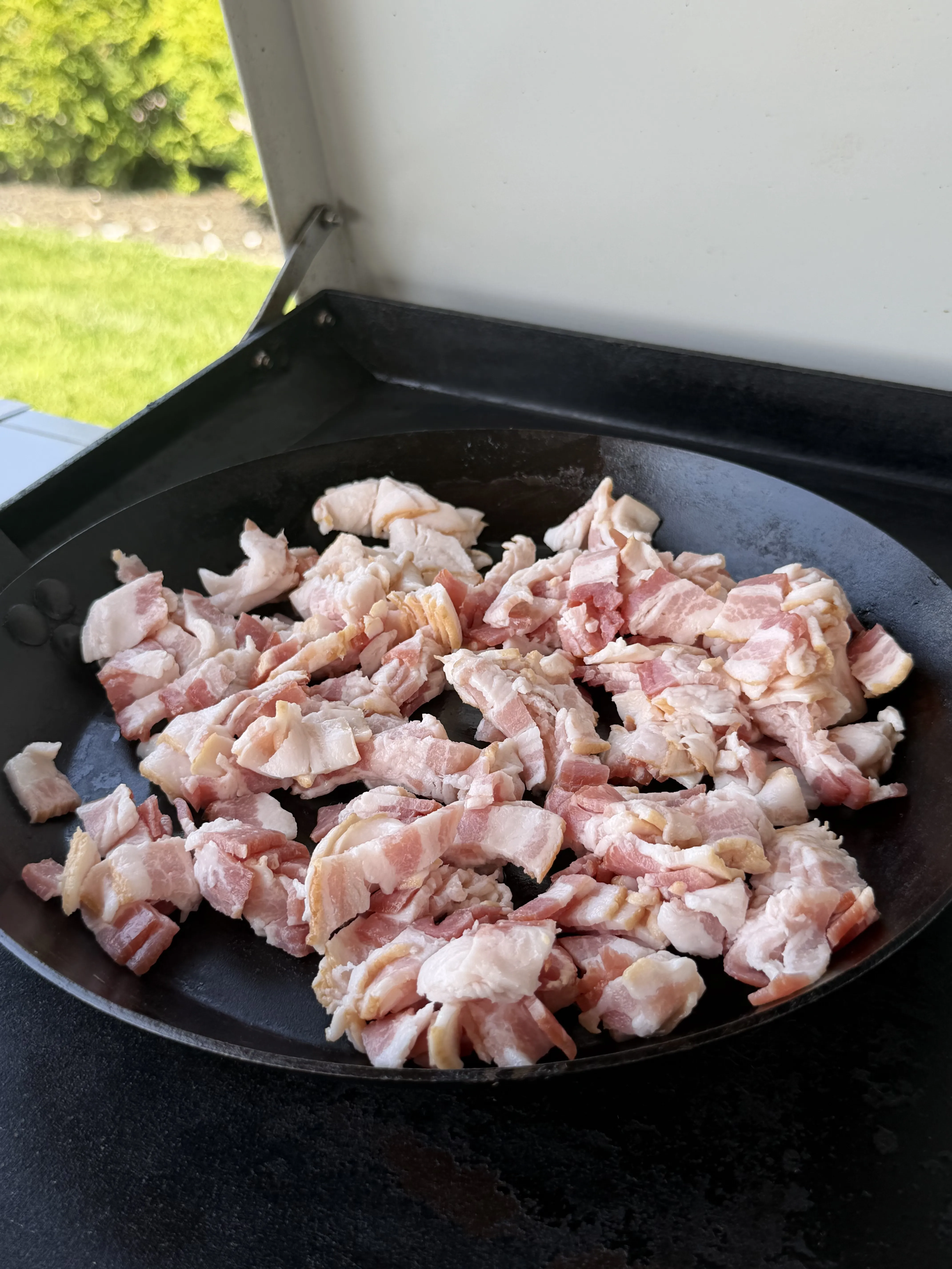 Diced thick-cut bacon cooking in a cast iron pan for bacon jam