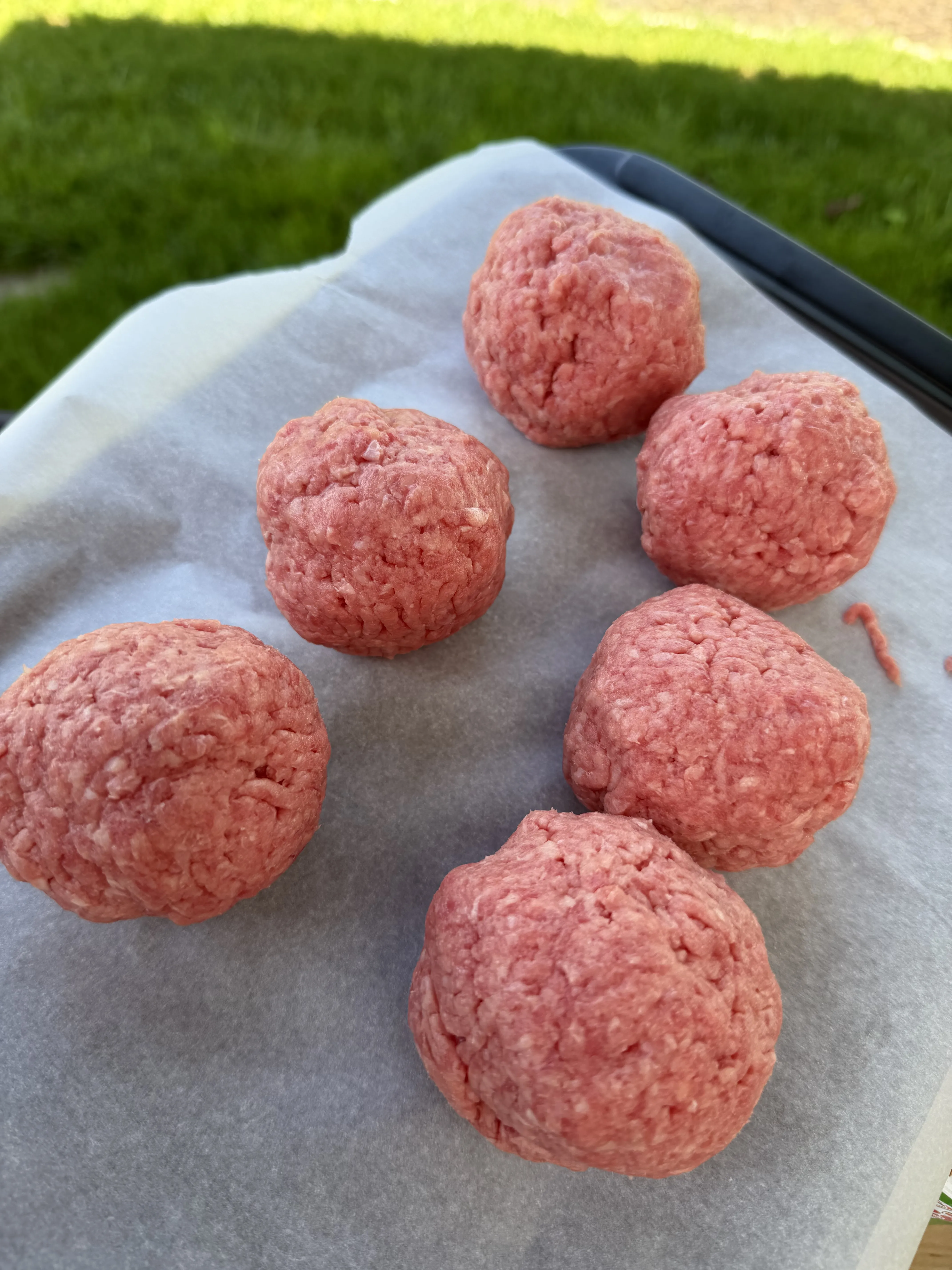 Eight loosely packed Cajun-seasoned ground beef balls on a baking sheet
