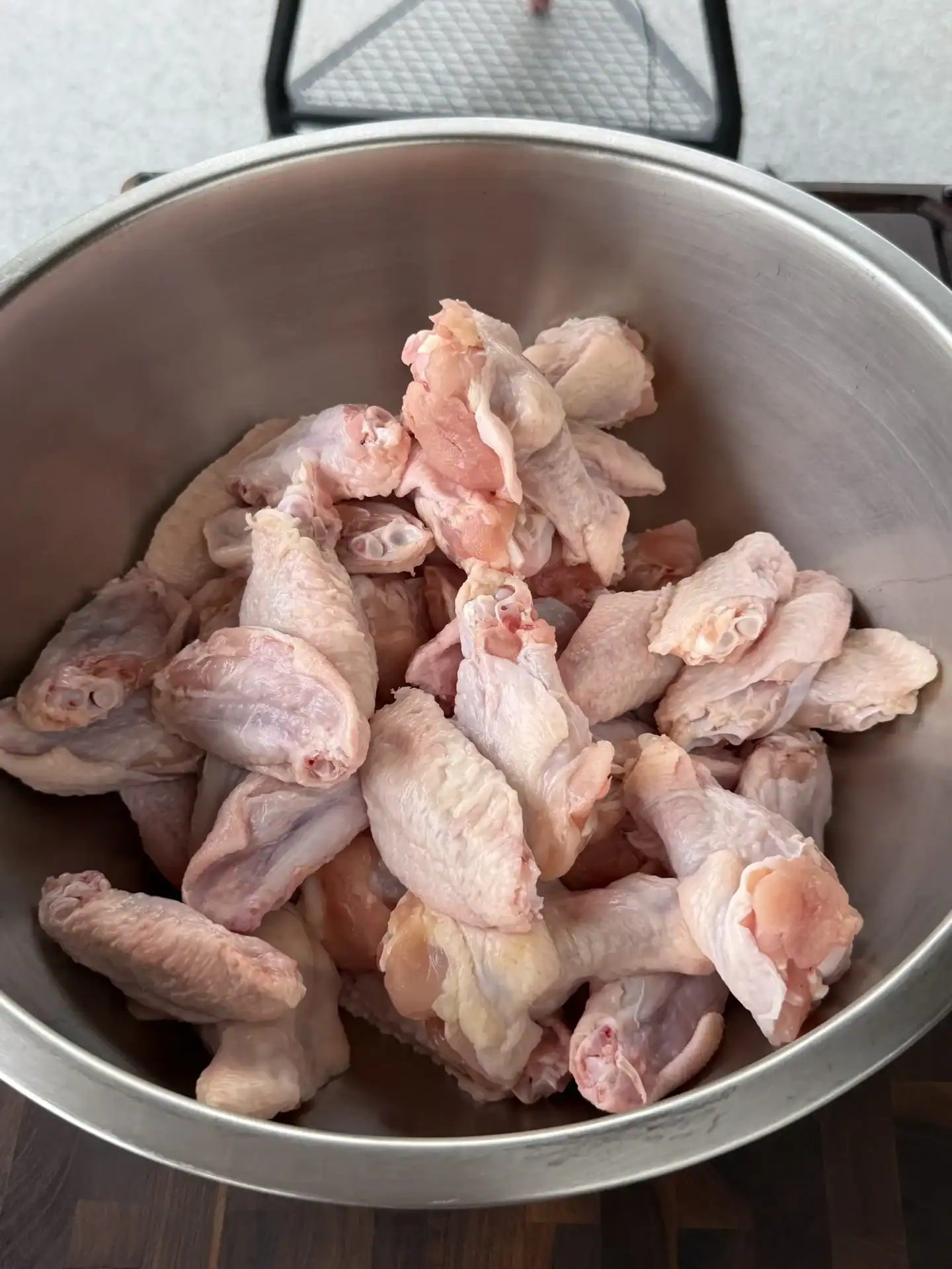 Raw chicken wings in a stainless steel bowl ready for cooking hot honey lemon pepper recipe.