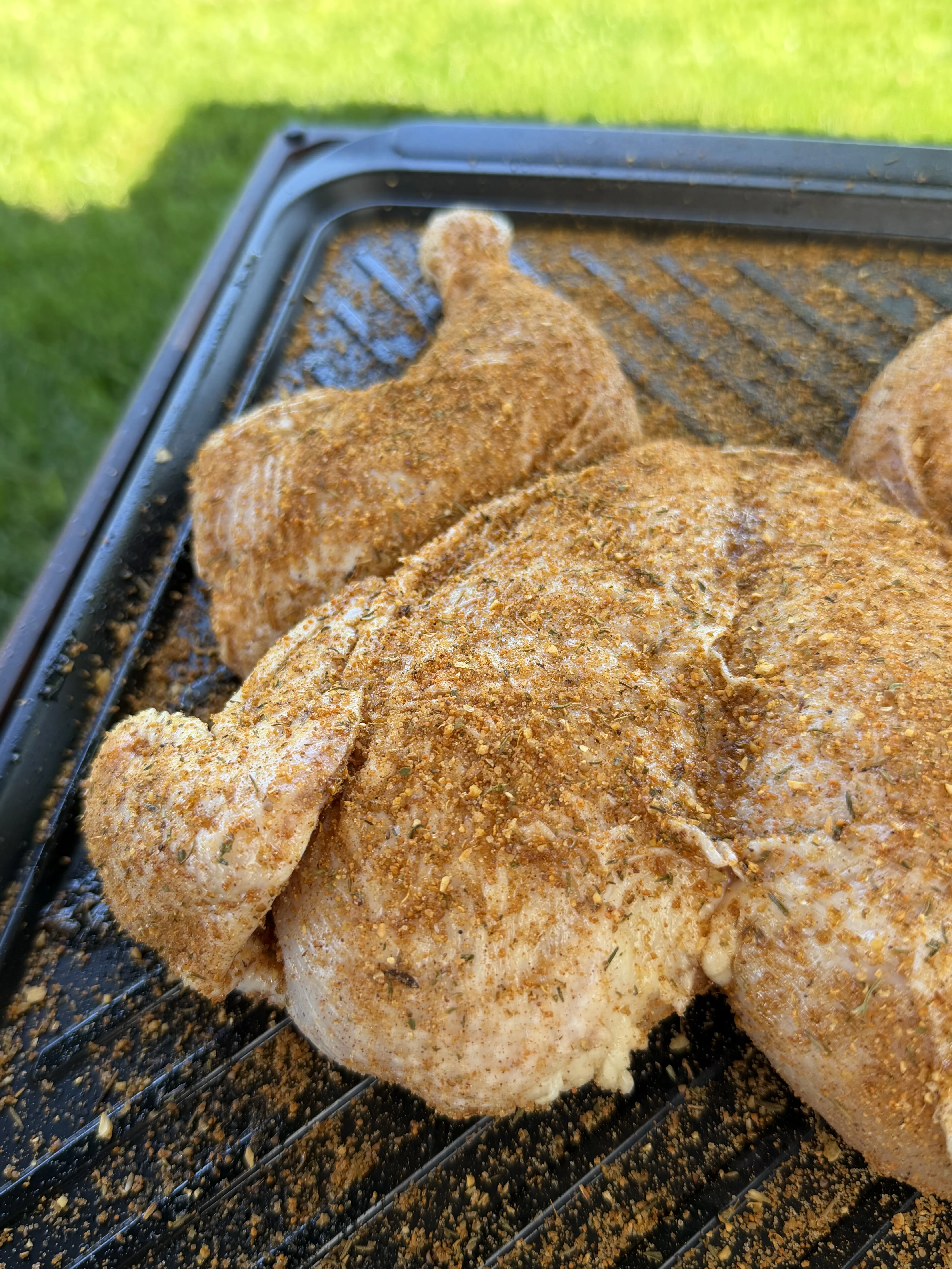 Spatchcock chicken cooking on the grill grates with golden skin developing