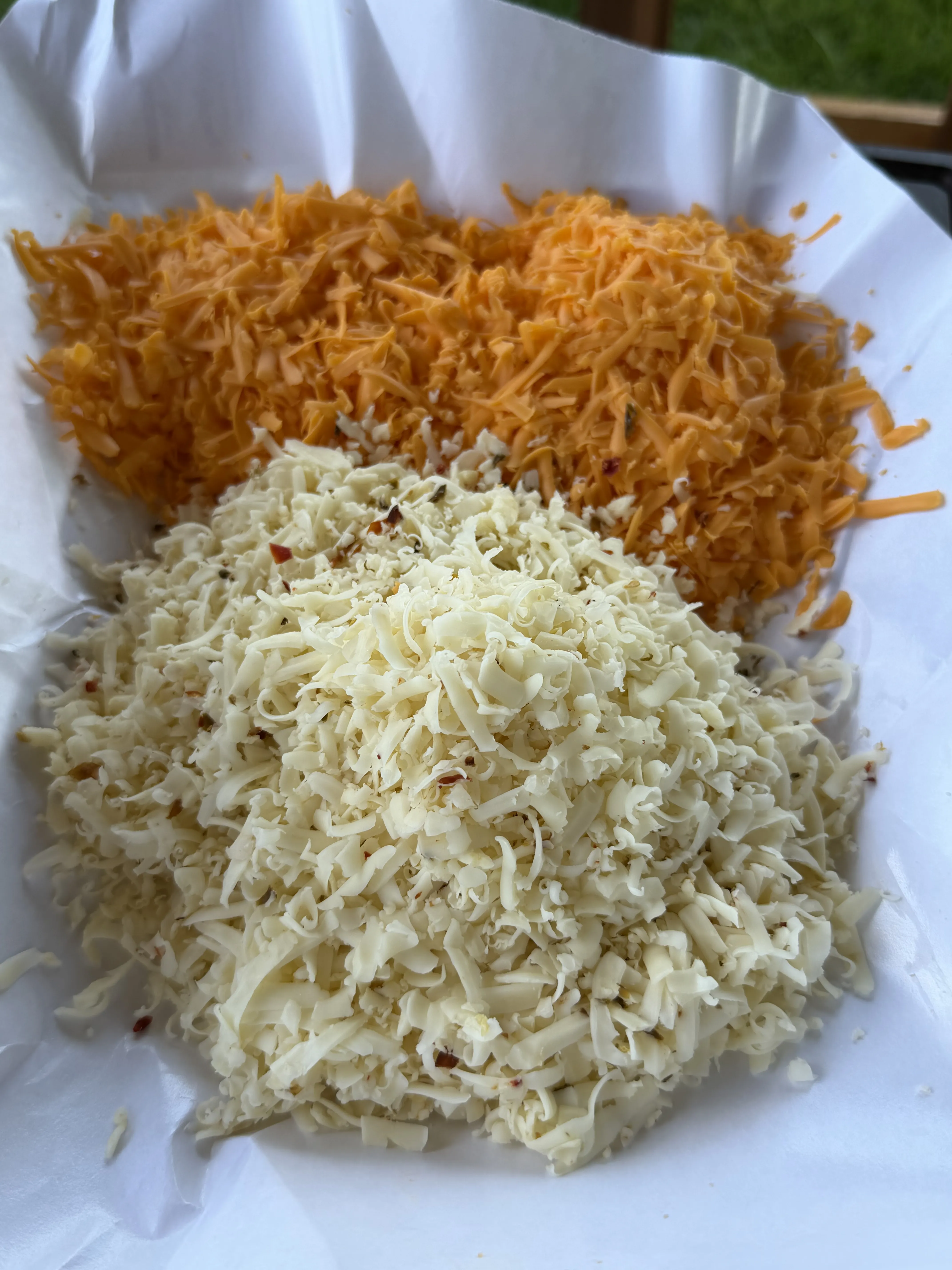Freshly shredded Pepper Jack and sharp cheddar cheese on parchment paper