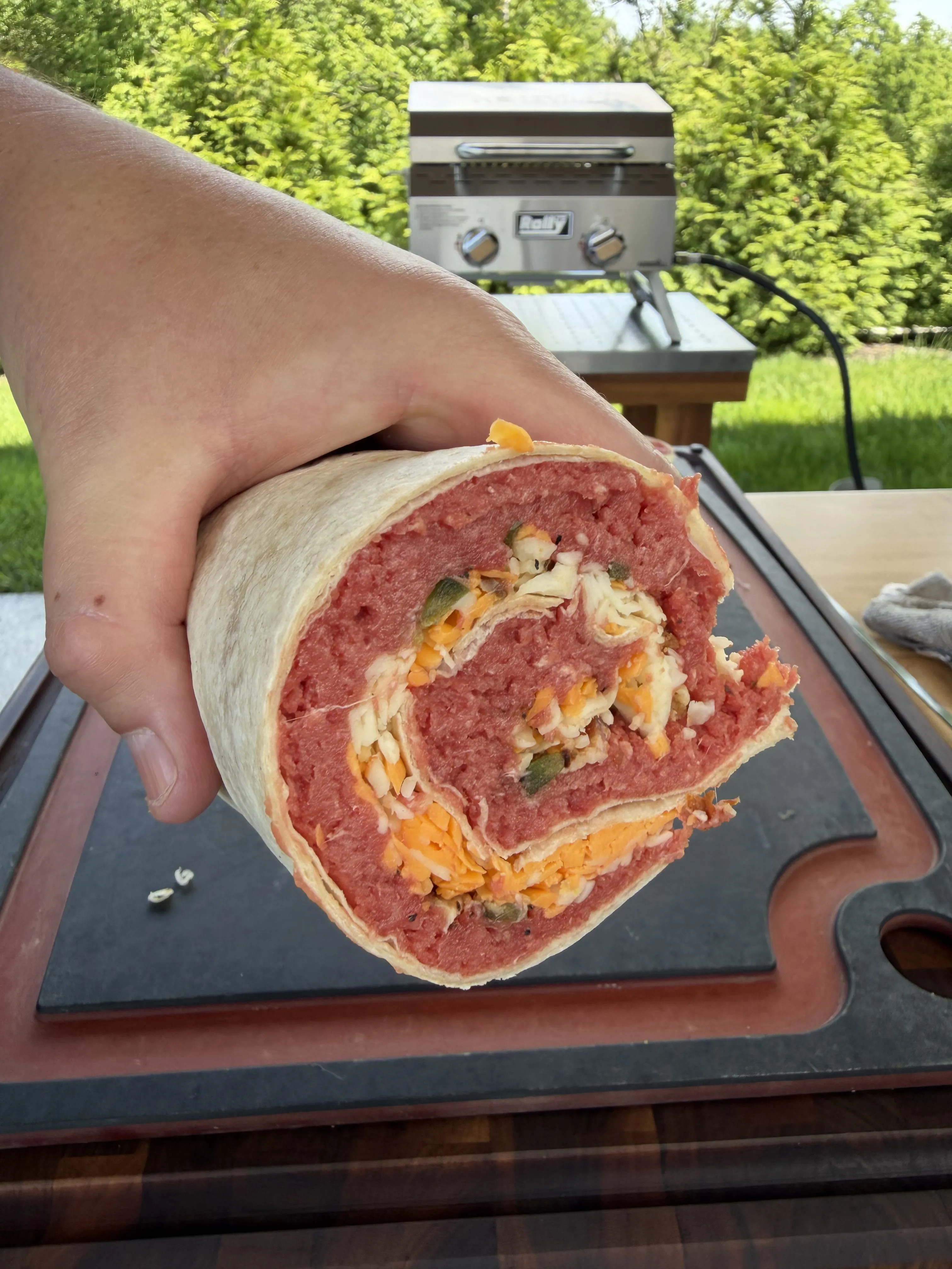Sliced beef pinwheels on a slate board showing layers of meat, cheese, and jalapeños