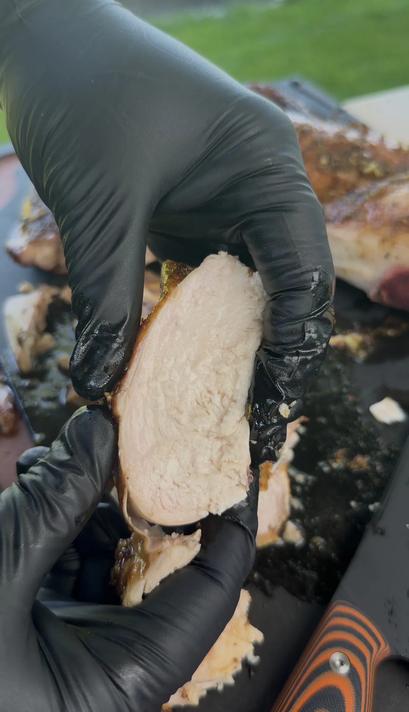 Hands slicing the rested spatchcock chicken before serving