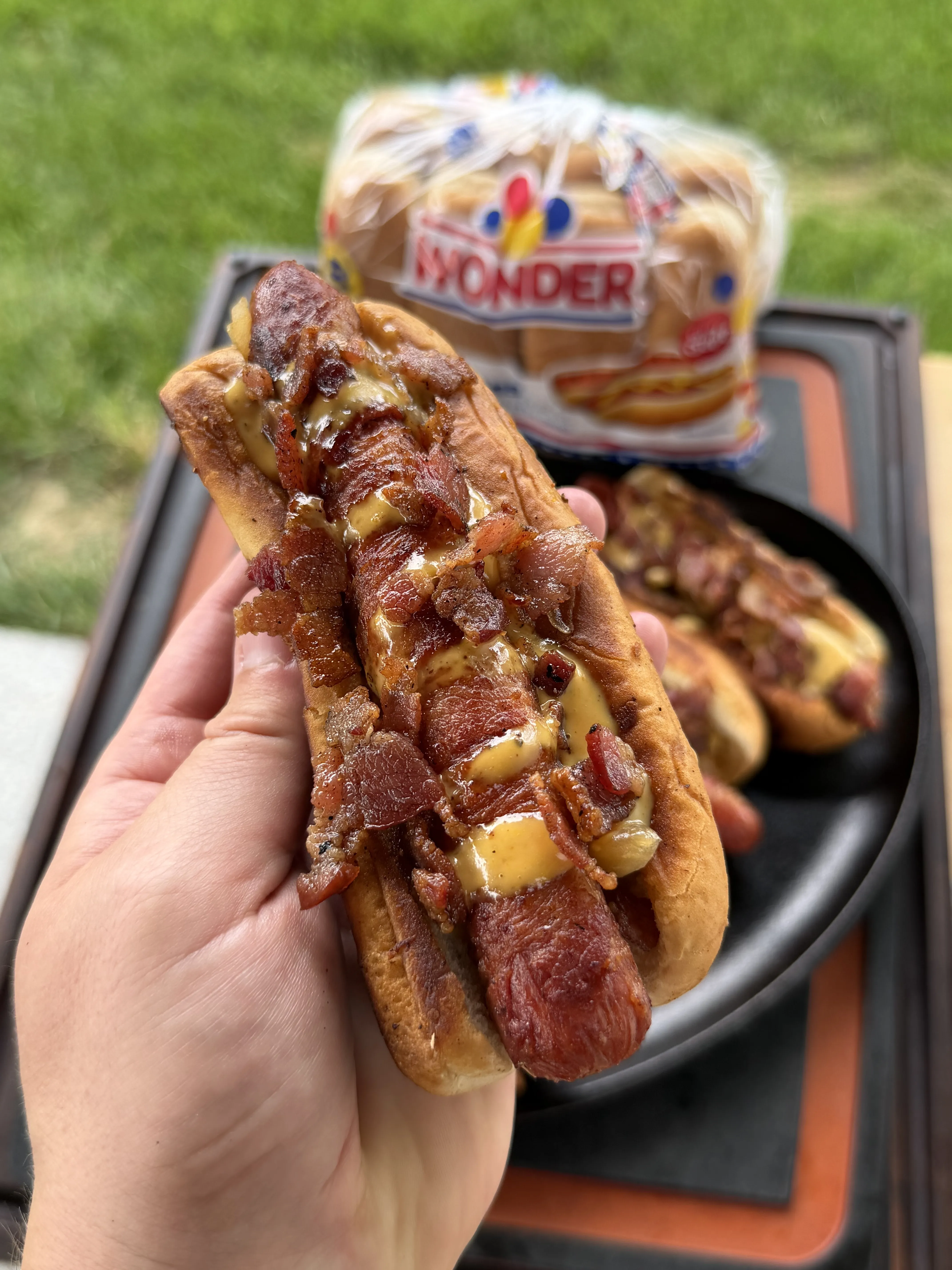 Assembled baconnaise loaded hot dog topped with crispy bacon and creamy sauce in a toasted bun