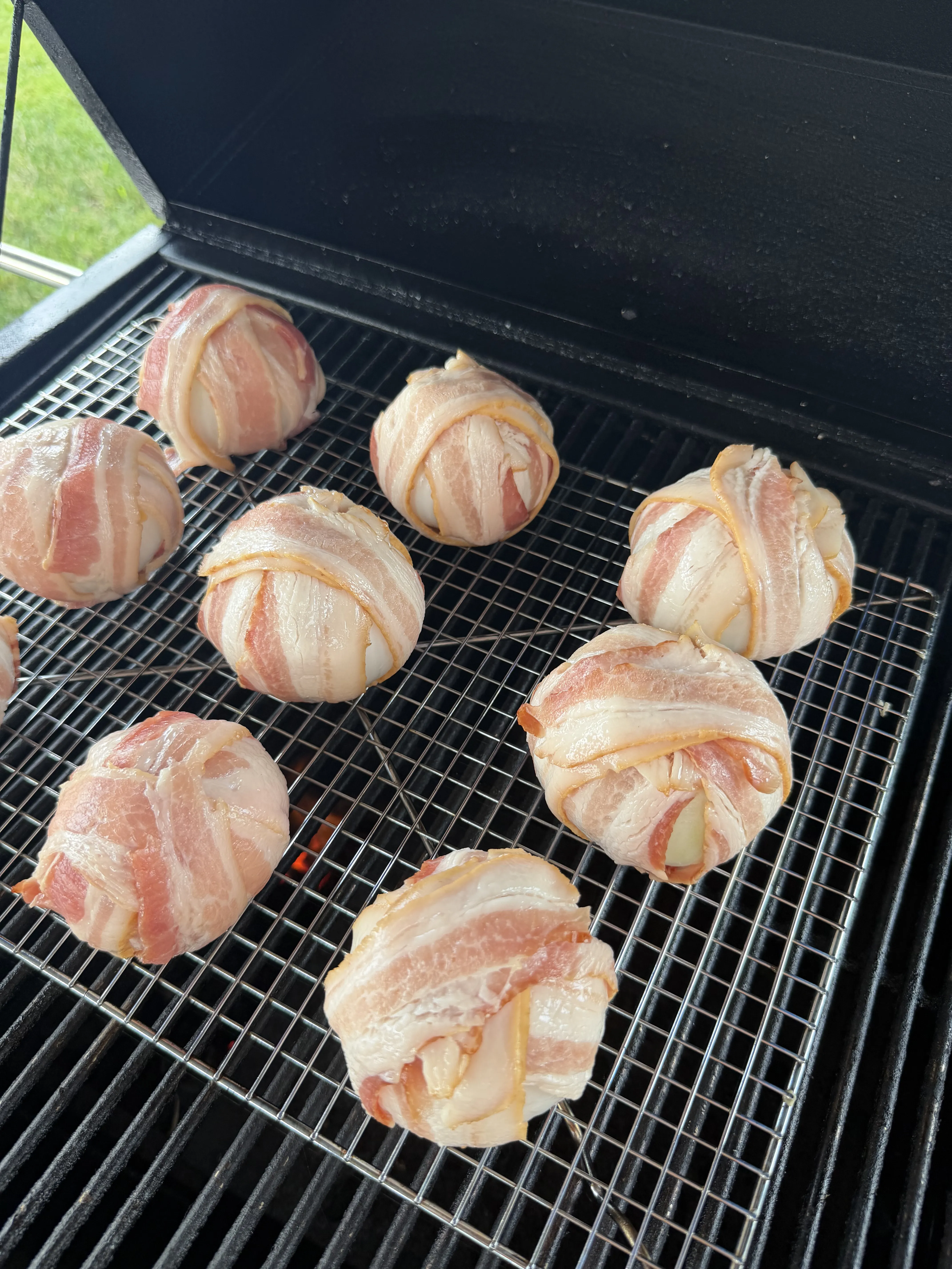 Raw bacon wrapped onion bombs on a wire rack inside the smoker at 325 degrees
