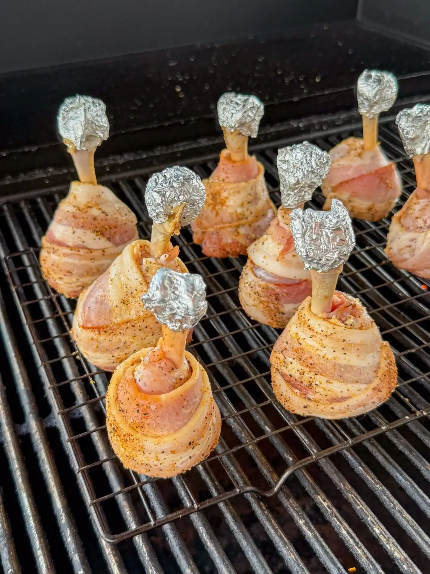 Bacon wrapped chicken lollipops smoking upright at 325°F