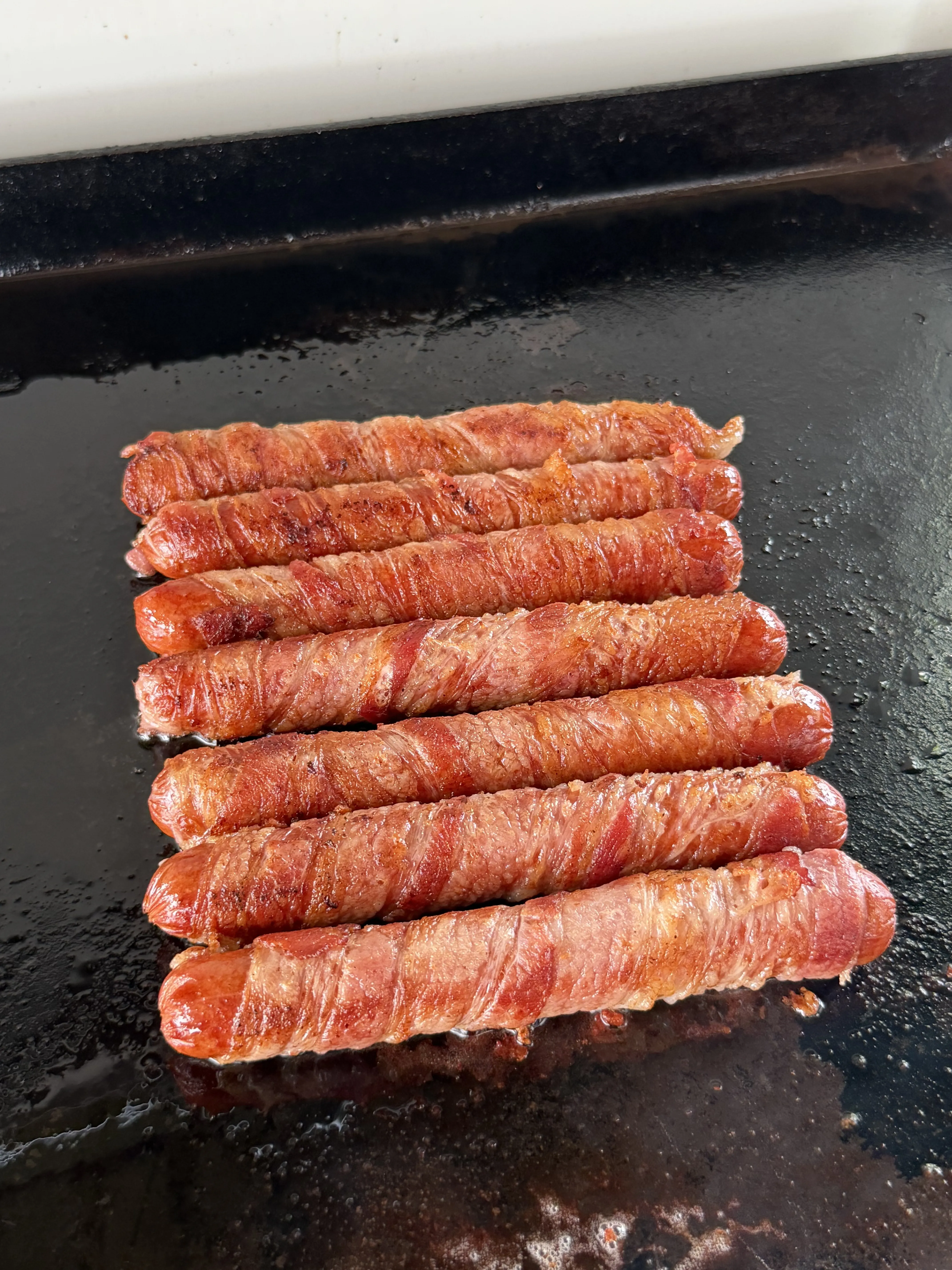 Bacon wrapped hot dogs golden brown and crispy as the bacon finishes rendering