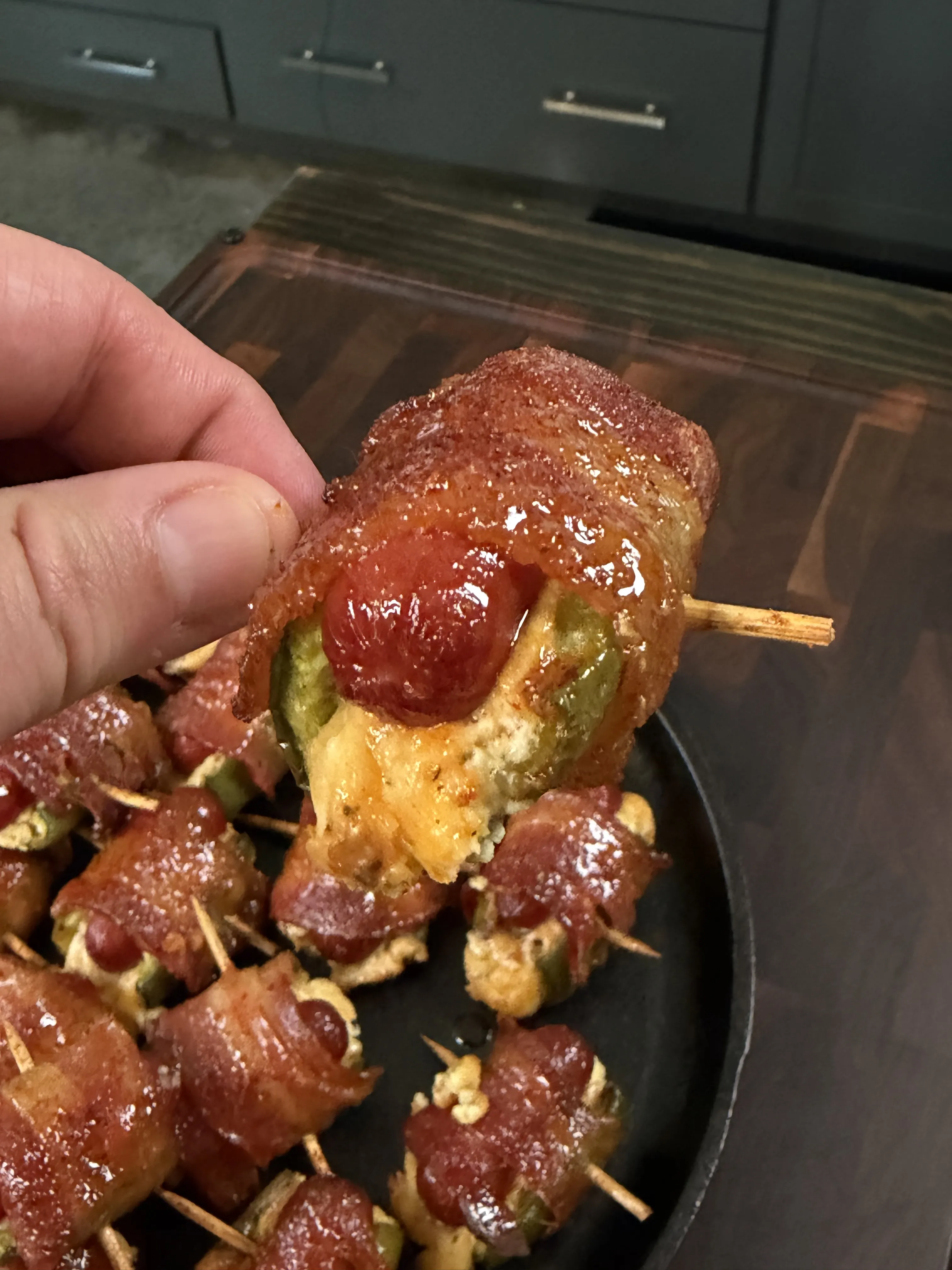 Bacon wrapped jalapeño smokie bomb with melted cheese and glazed bacon in a cast iron skillet