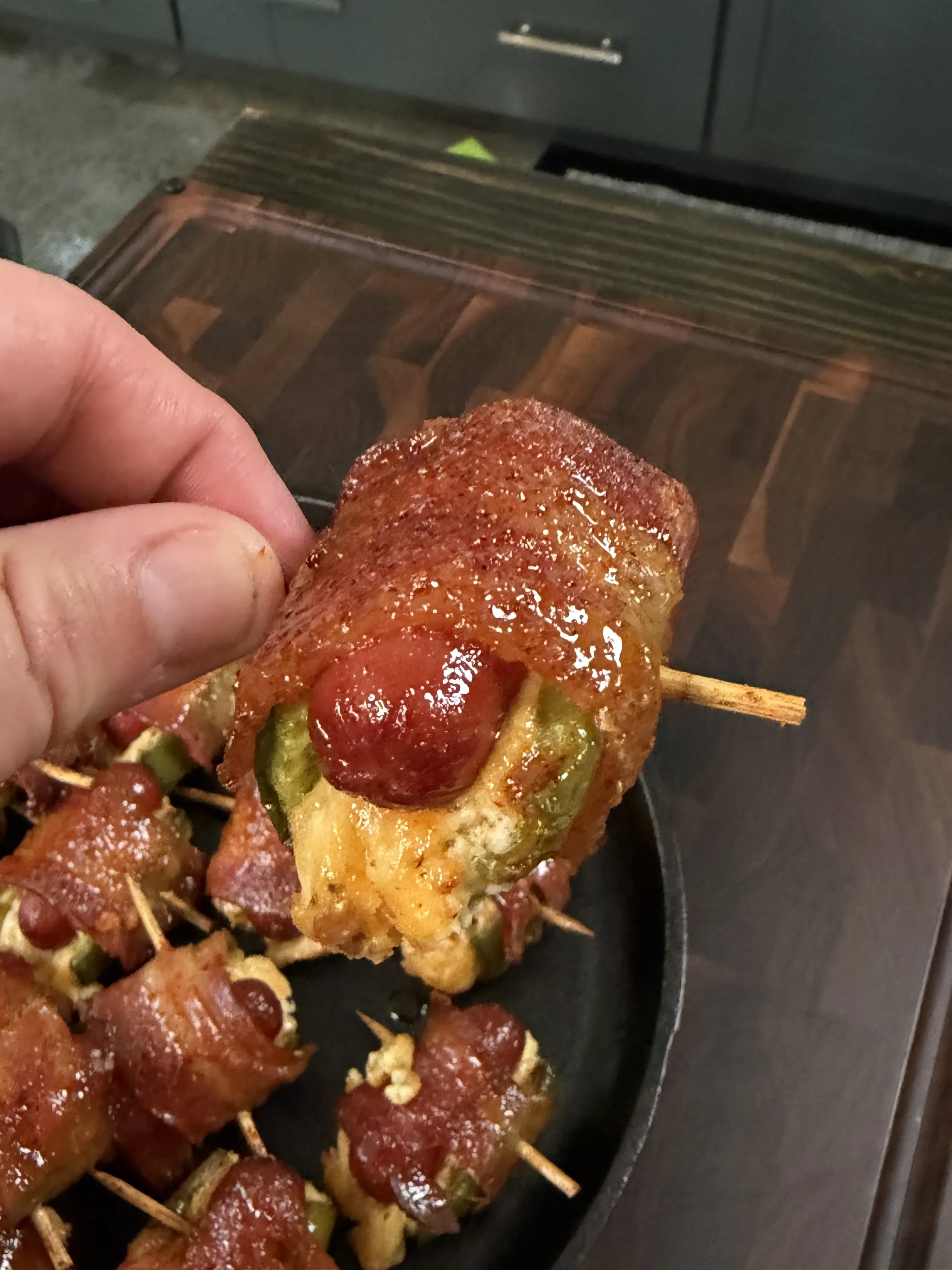 Close-up of a glazed bacon wrapped jalapeño smokie bomb filled with melted cheese