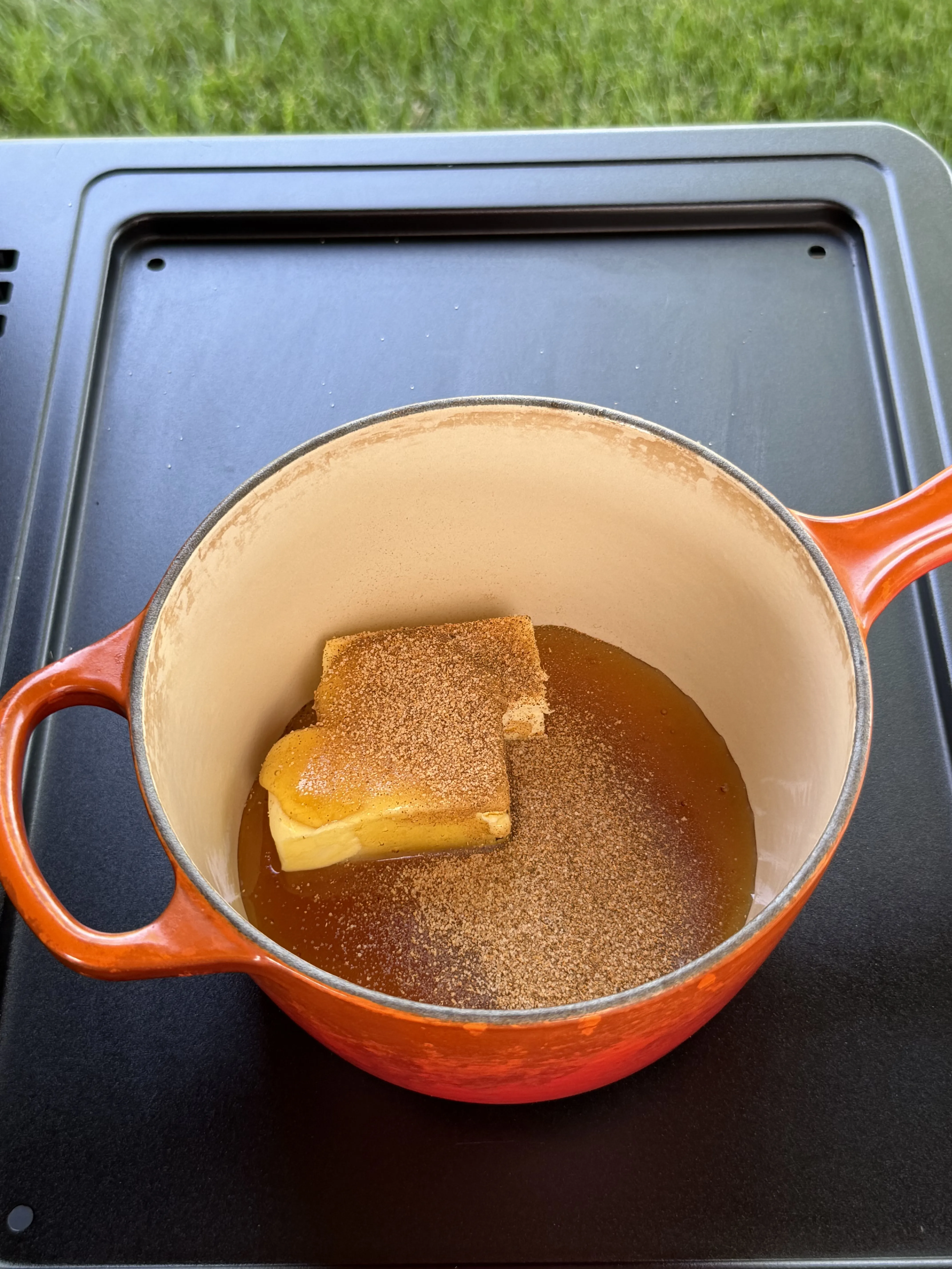 Butter, honey, and Tony's Creole seasoning melting together for the smoked shrimp baste in an orange Dutch oven