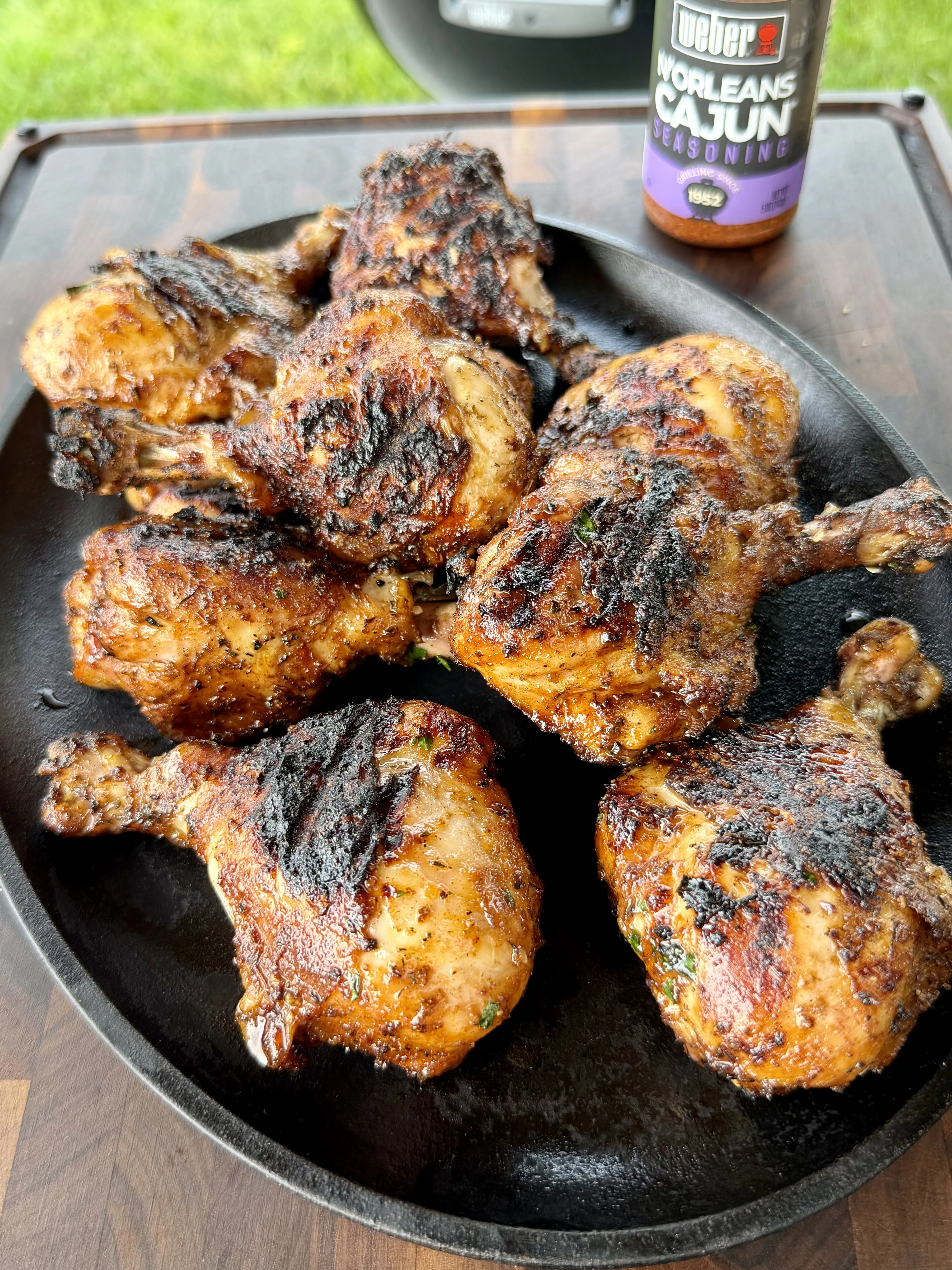 Charred Cajun-seasoned grilled chicken drumsticks piled on a black cast iron platter with Weber N'Orleans Cajun seasoning