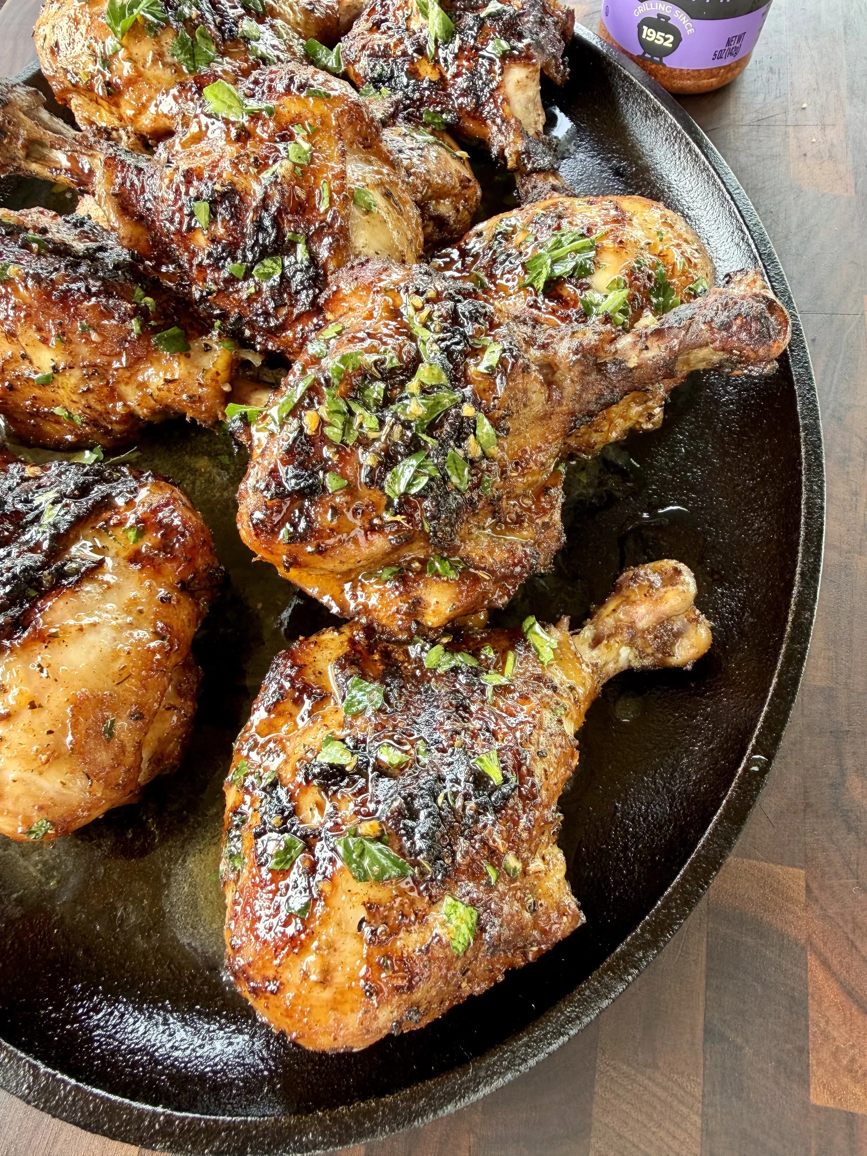 Juicy Cajun grilled chicken drumsticks glazed with BBQ sauce and topped with fresh herbs in a cast iron skillet