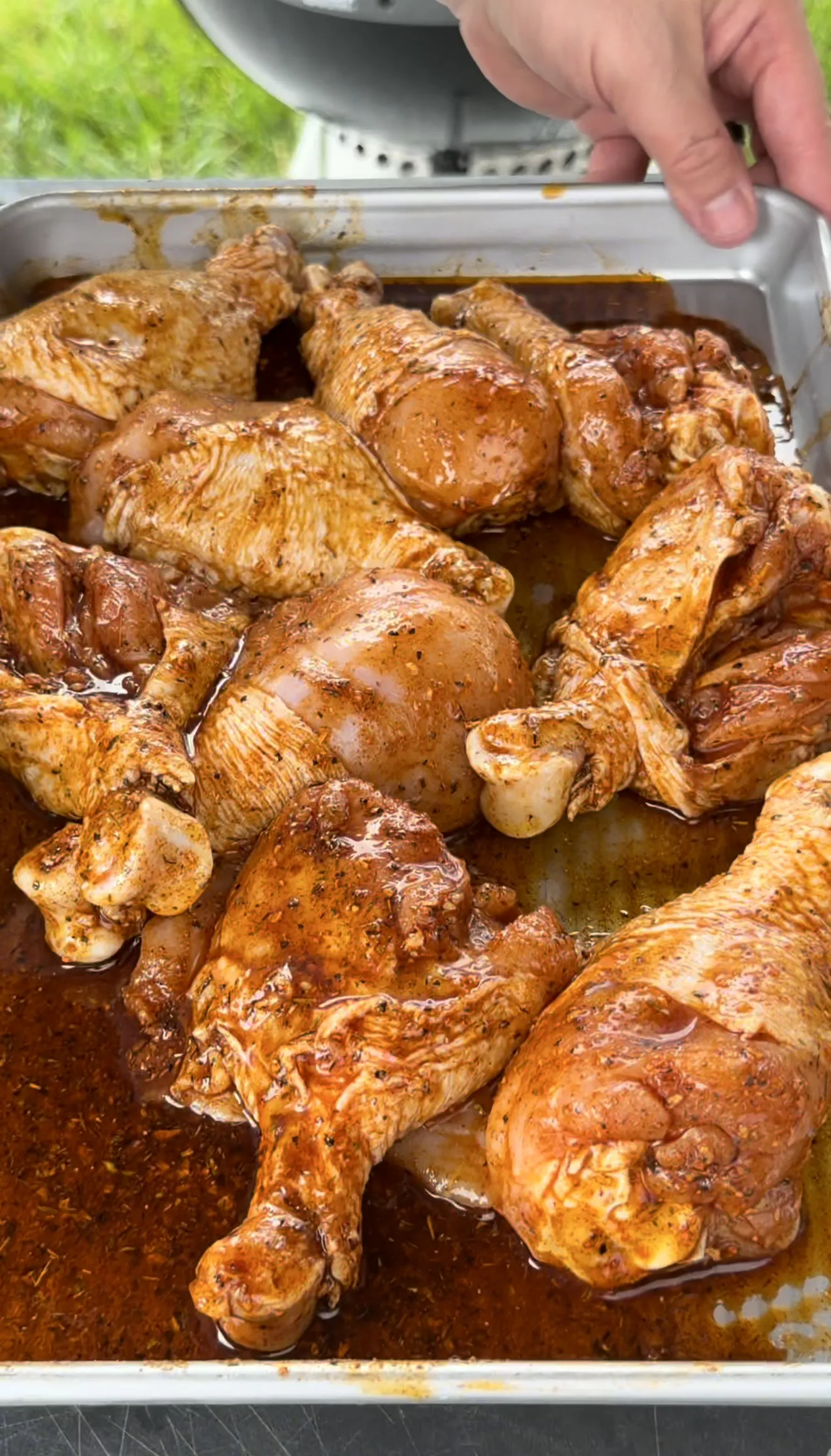 Seasoned Cajun chicken drumsticks glazed in spicy marinade resting in a metal roasting pan with drippings