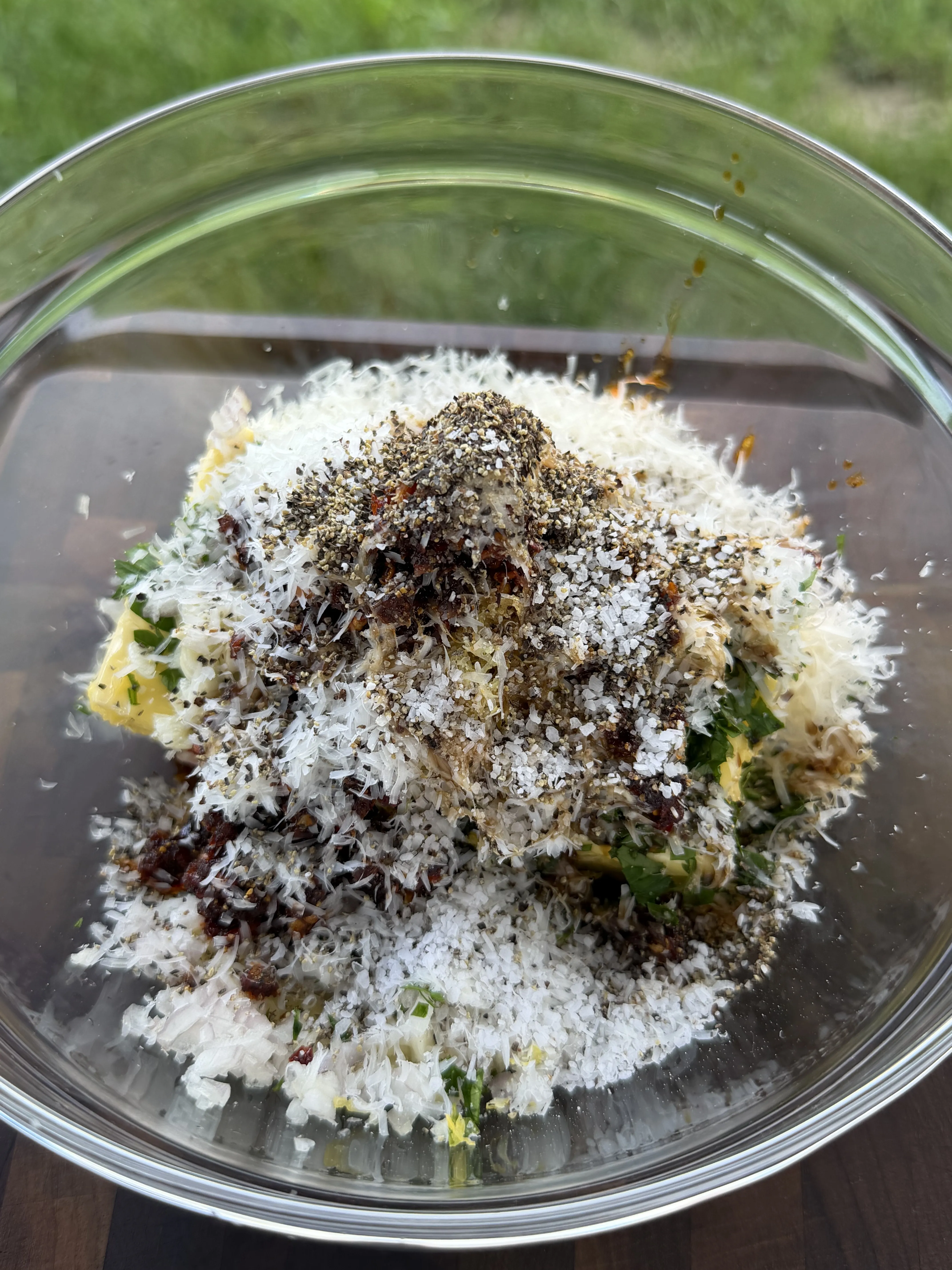 Glass bowl with butter, grated Parmesan, fresh herbs, chili flakes, and cracked black pepper