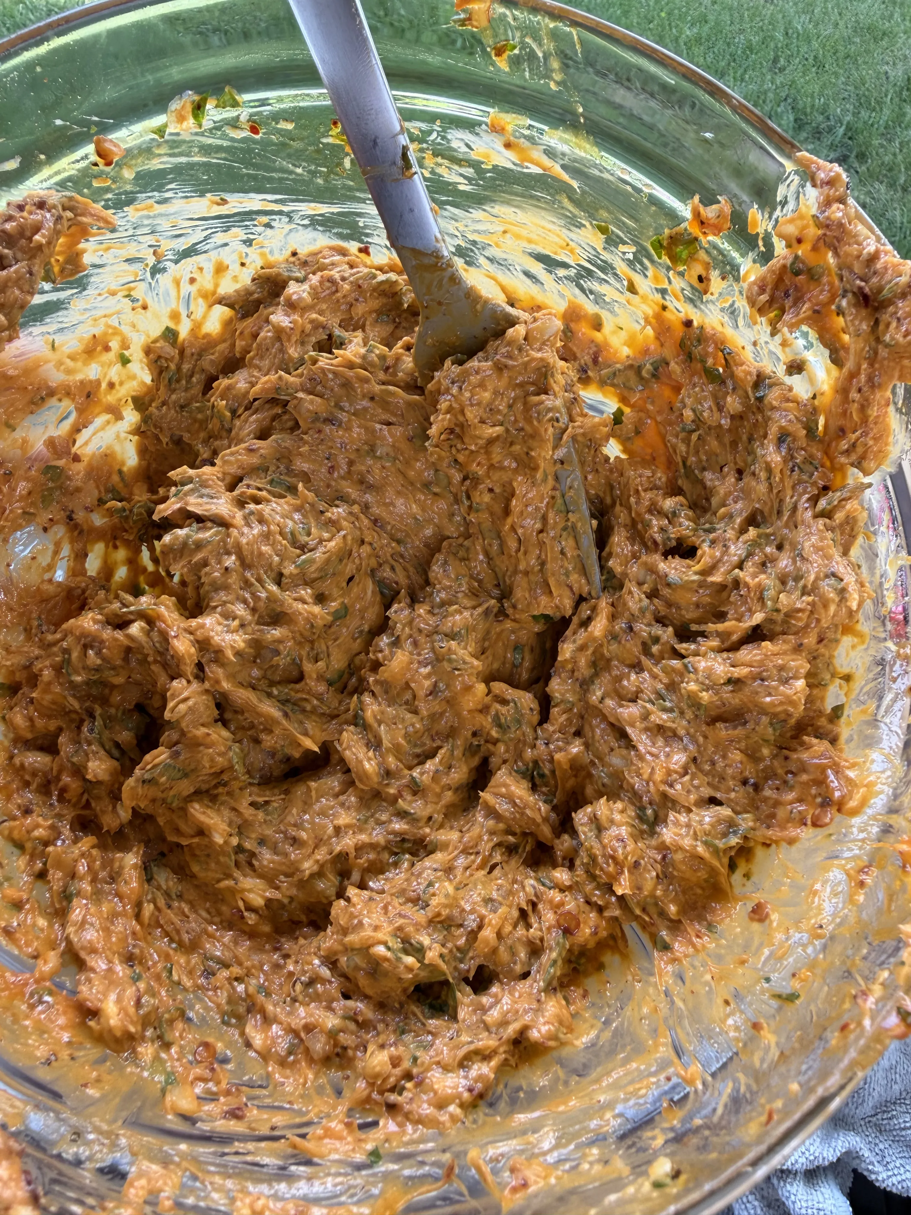 Chili parmesan compound butter stirred into a rich orange-red blend in a glass bowl