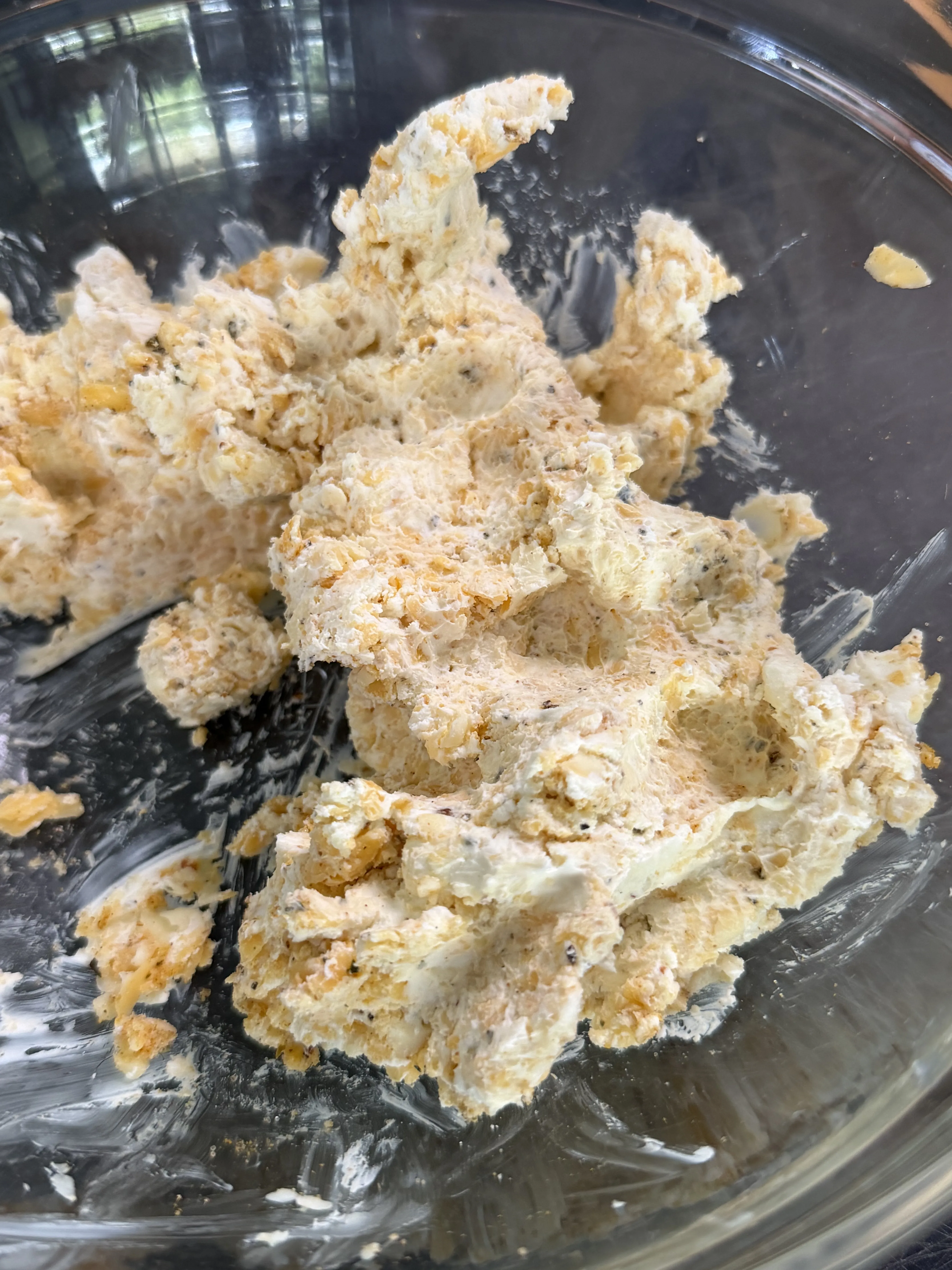 Three-cheese filling mixture for jalapeño smokie bombs in a glass mixing bowl