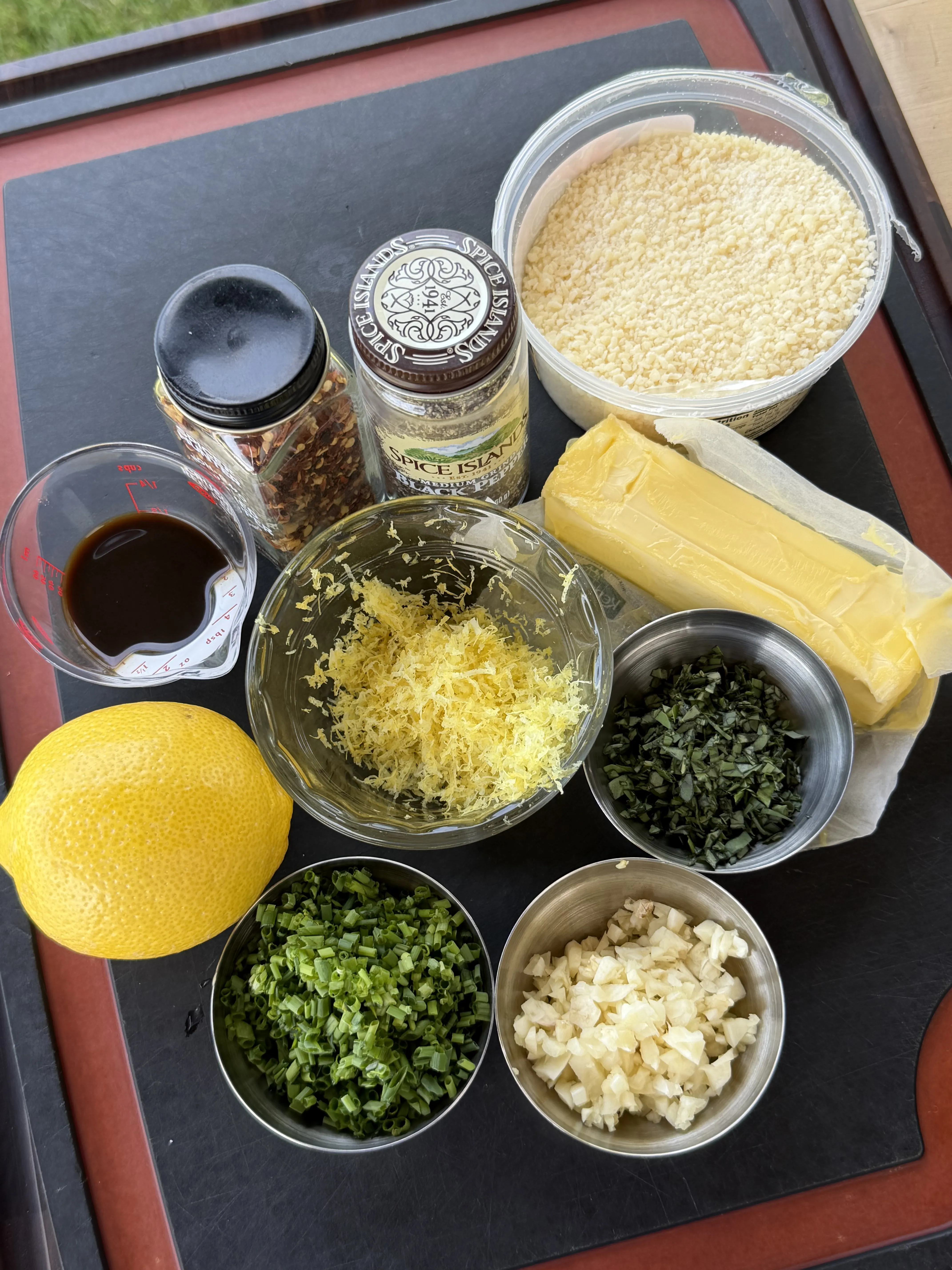 Butter, lemon zest, garlic, chives, fresh herbs, and spices laid out for compound butter
