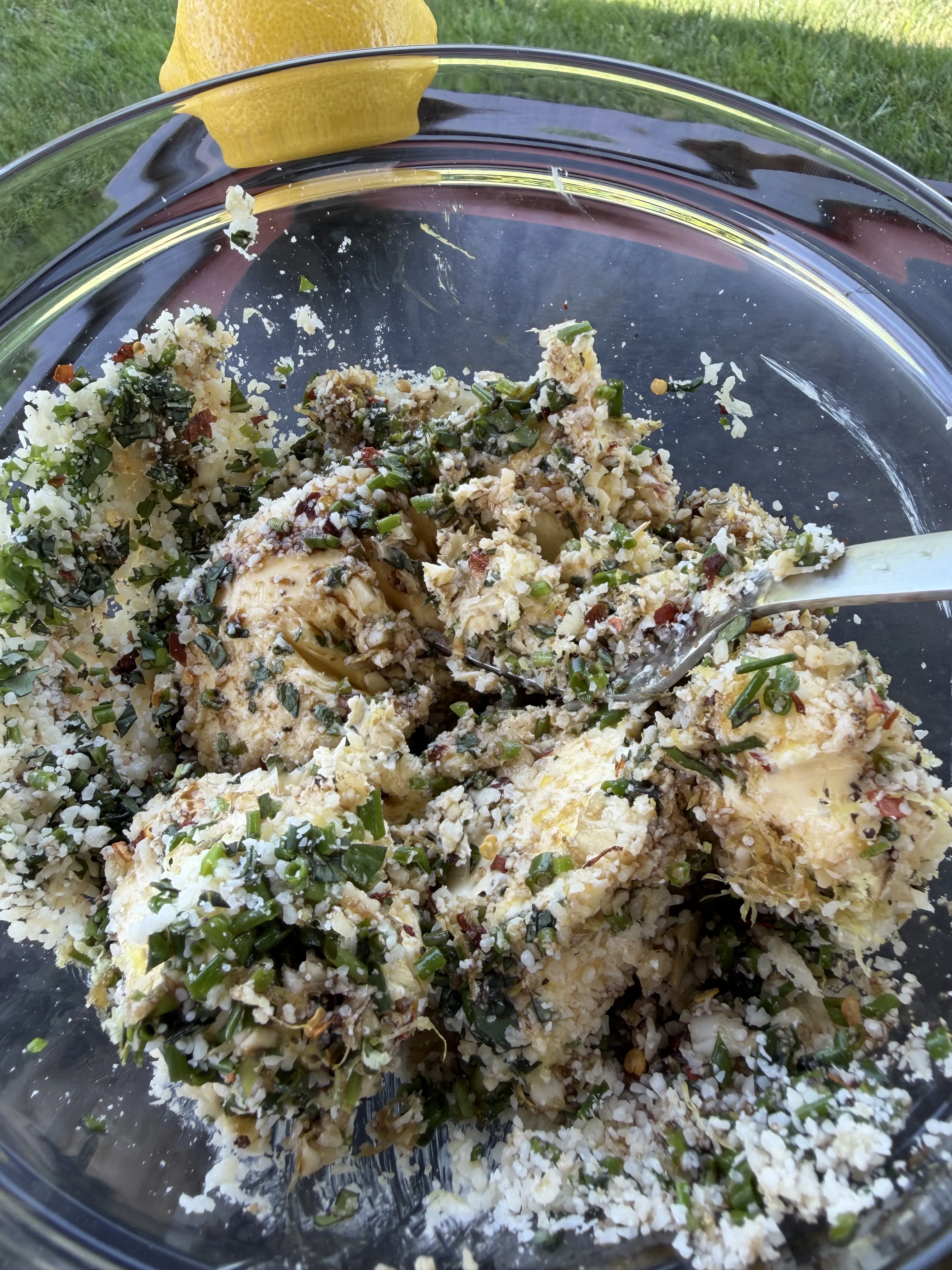 Compound butter mixture with fresh herbs and lemon in a glass mixing bowl