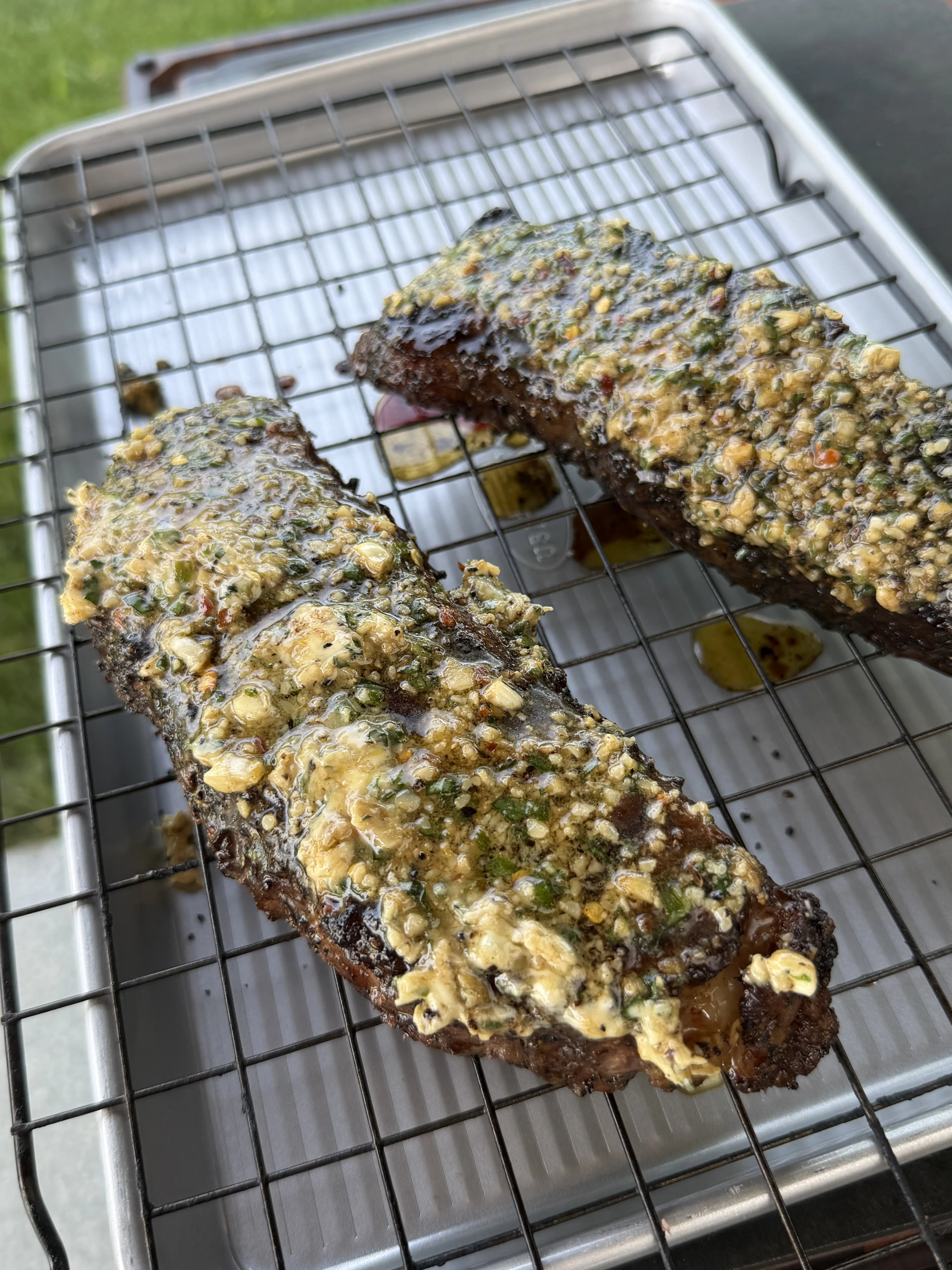 Melting compound butter running over a rack of grilled ribs on a wire rack