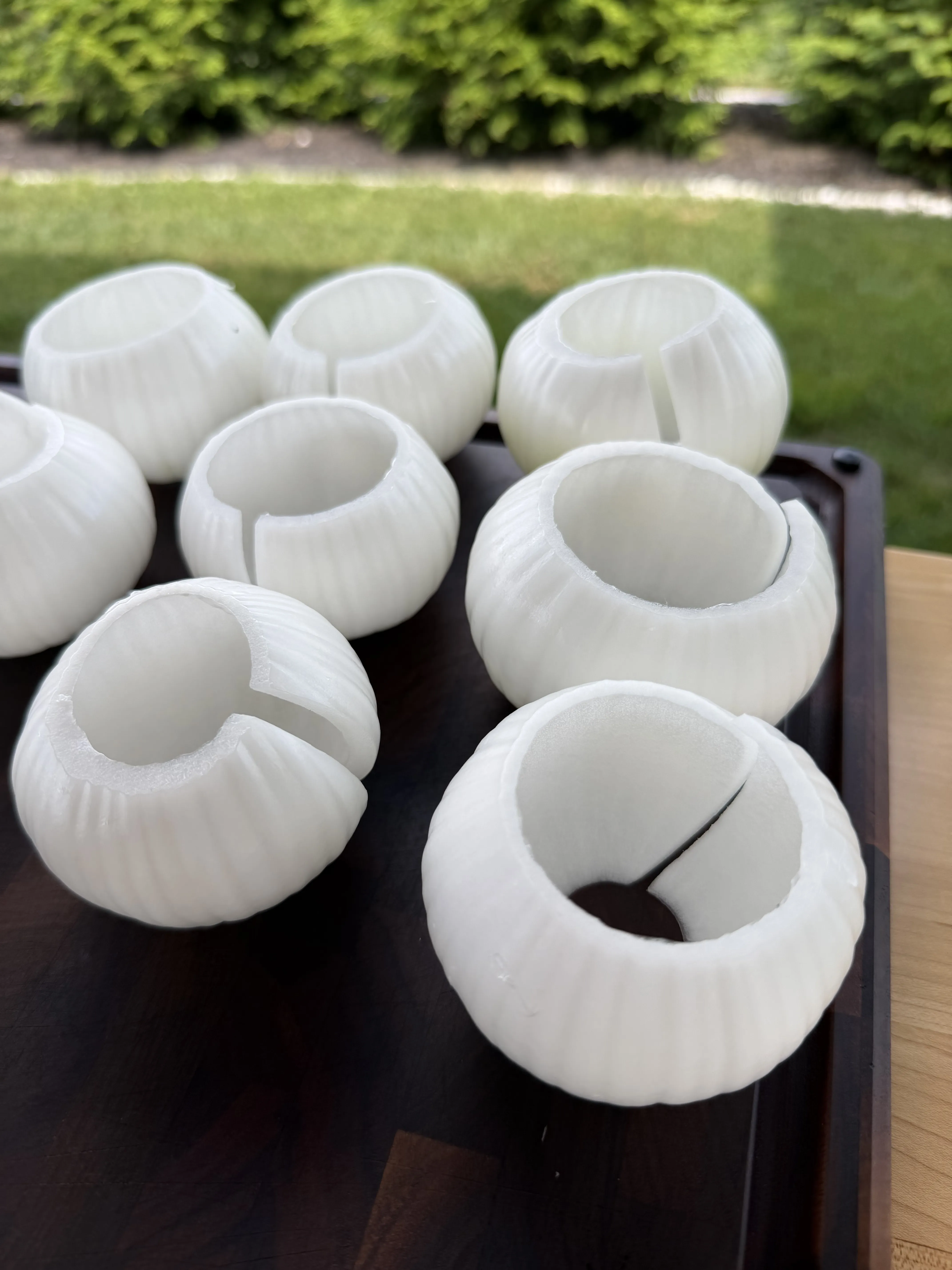 Hollowed sweet onion shells arranged on a wooden tray prepped for stuffing
