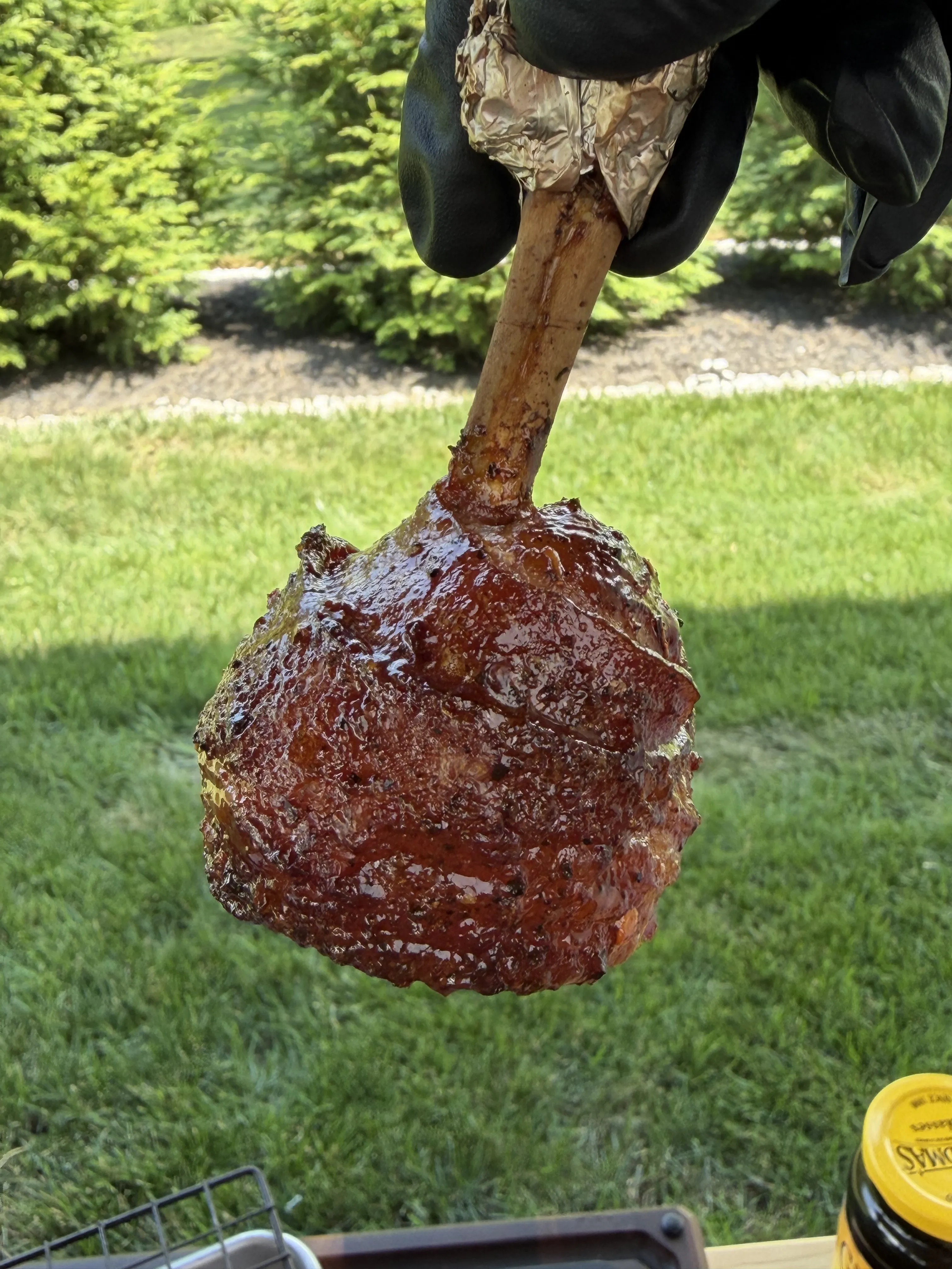 Glazed molasses candied bacon wrapped chicken lollipop with a deep caramelized crust