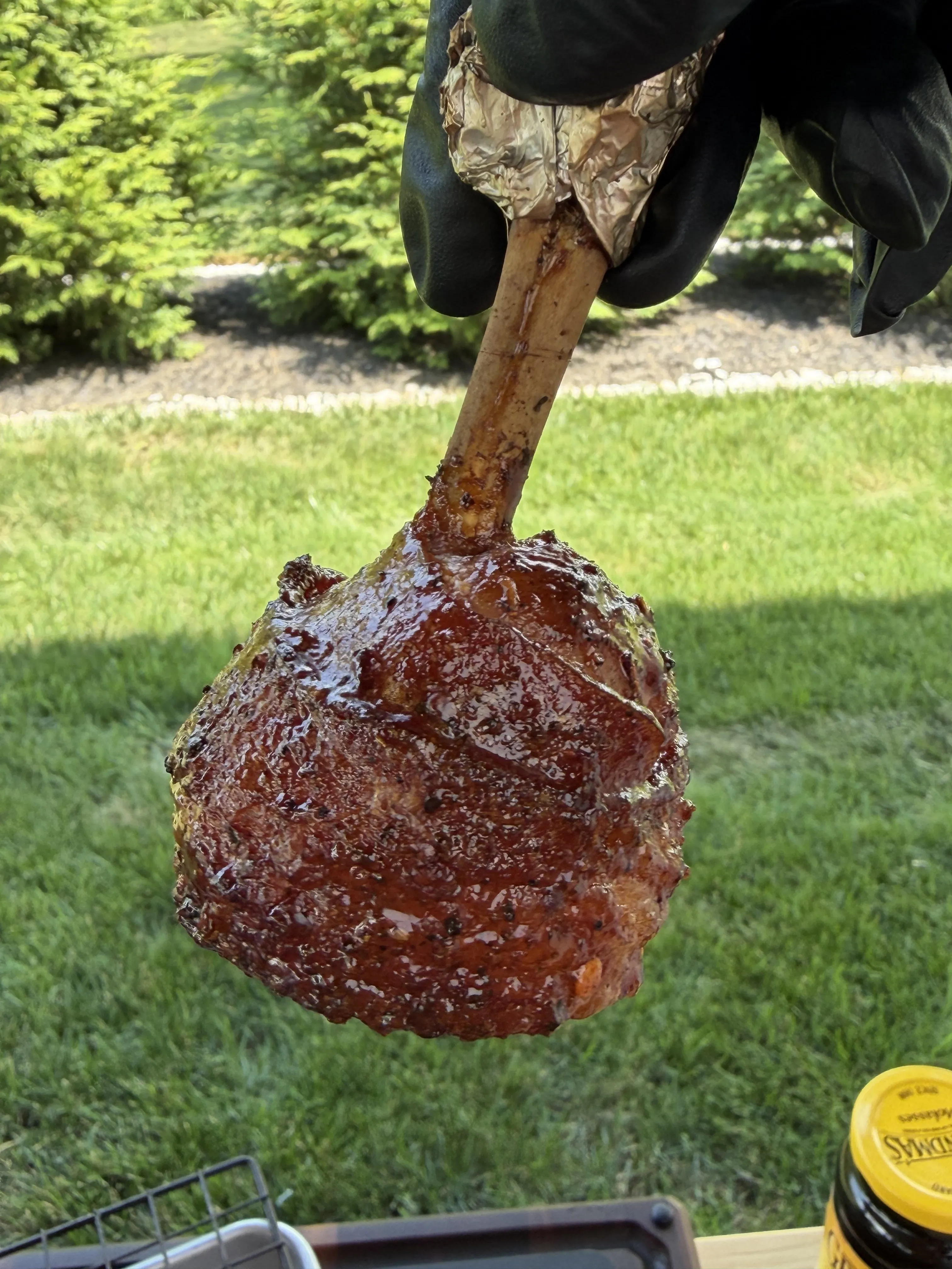 Finished molasses candied bacon wrapped chicken lollipop with a glossy caramelized crust