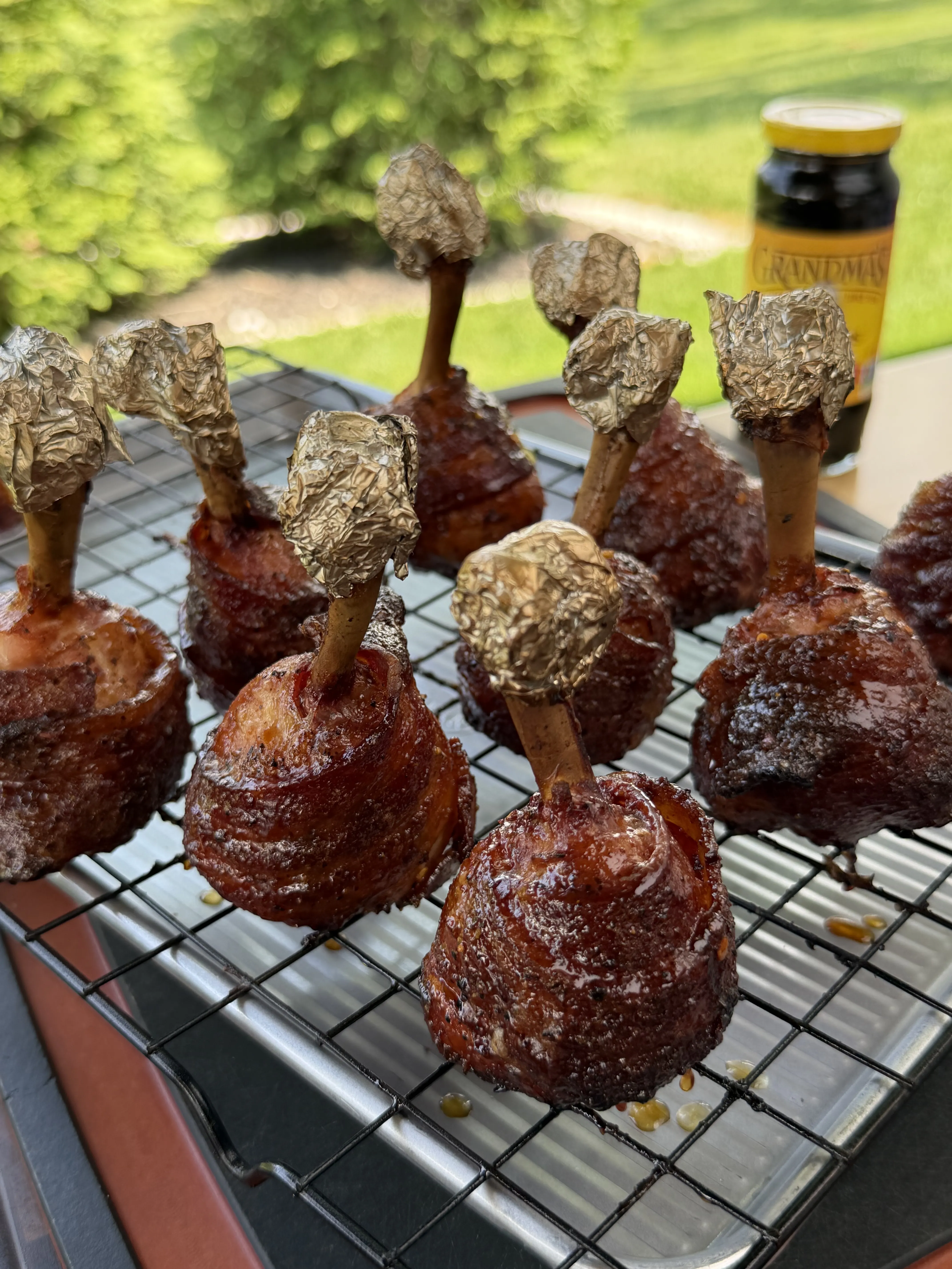 Bacon wrapped chicken lollipops glazed with molasses on the smoker grates