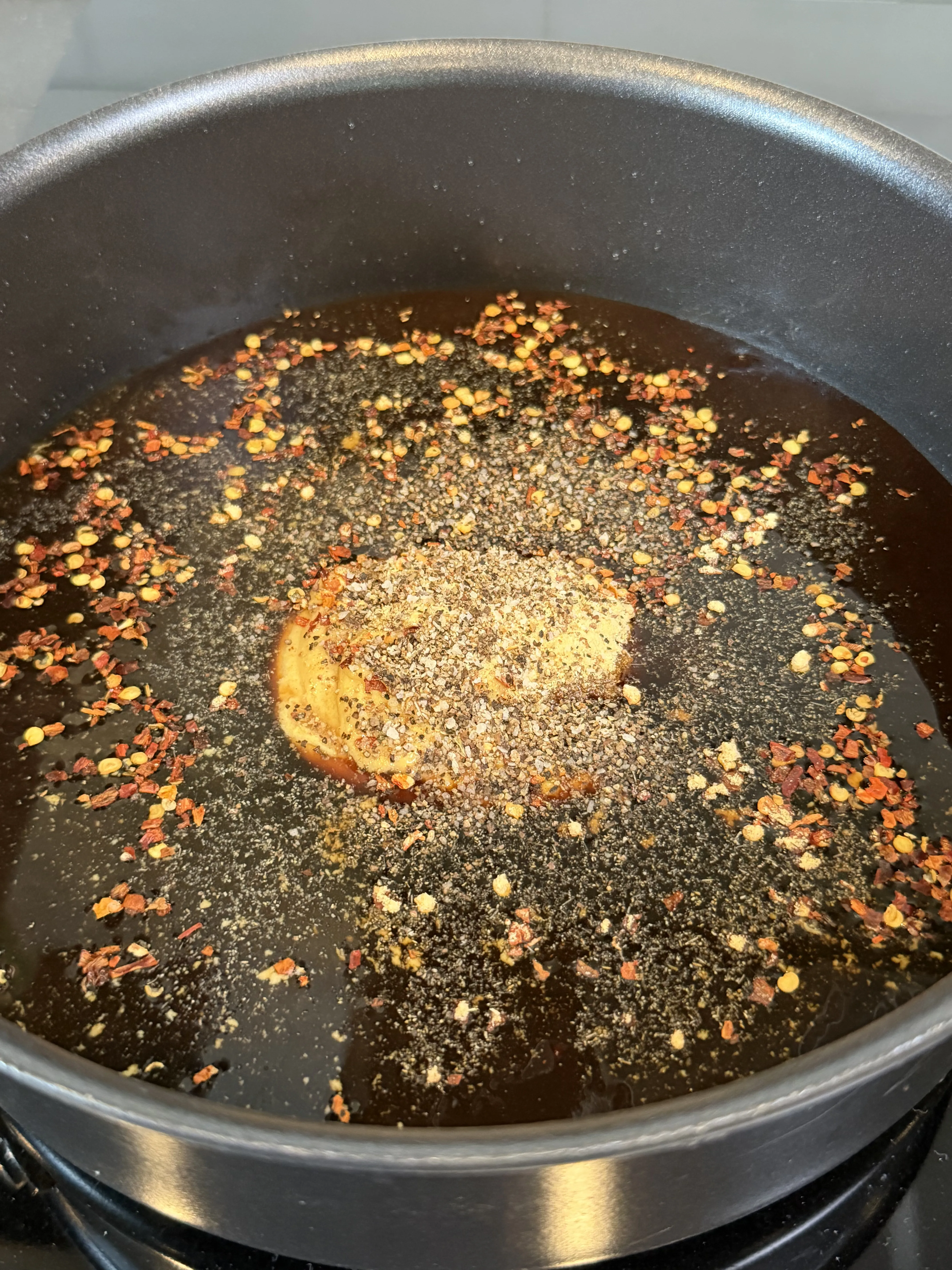 Molasses butter glaze simmering in a pan for the candied bacon chicken lollipops