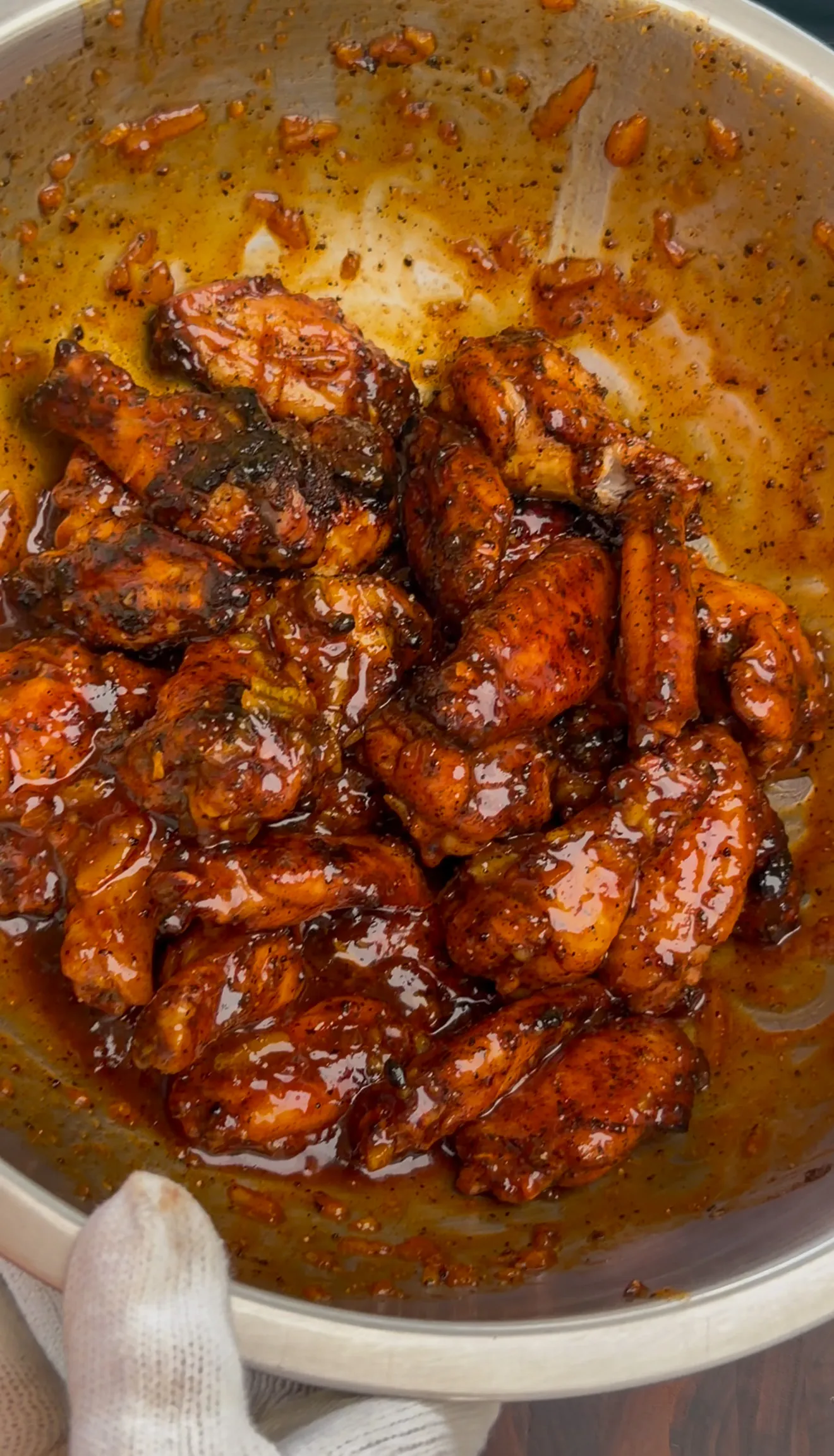 Wings glazed in orange gochujang BBQ sauce in a pan ready for garnish