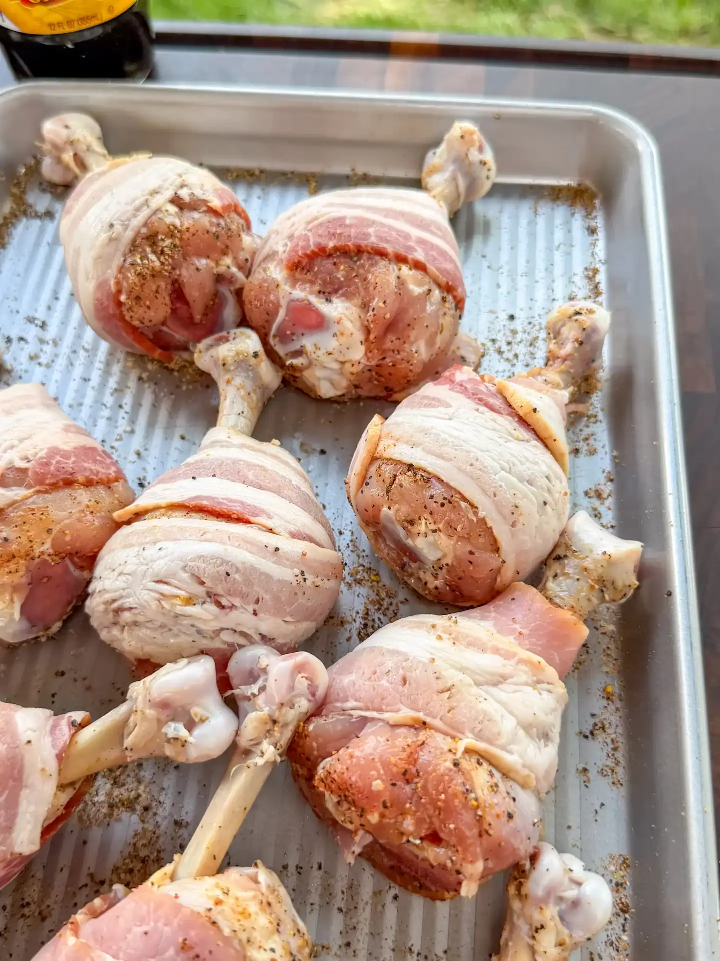 Seasoned chicken lollipops wrapped with thick-cut bacon before smoking