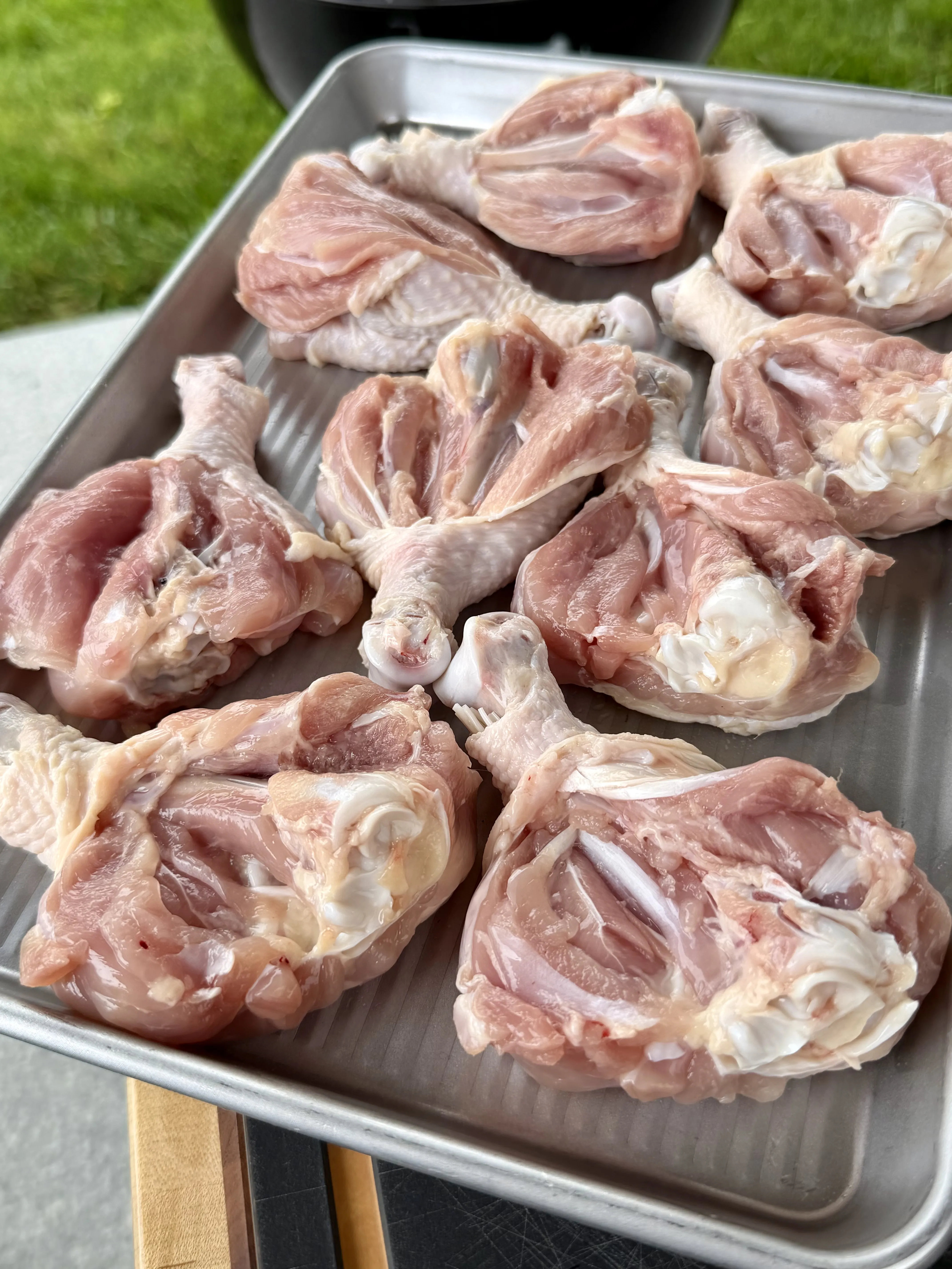 Raw chicken drumsticks arranged on a metal baking sheet, ready to be seasoned for Cajun grilling