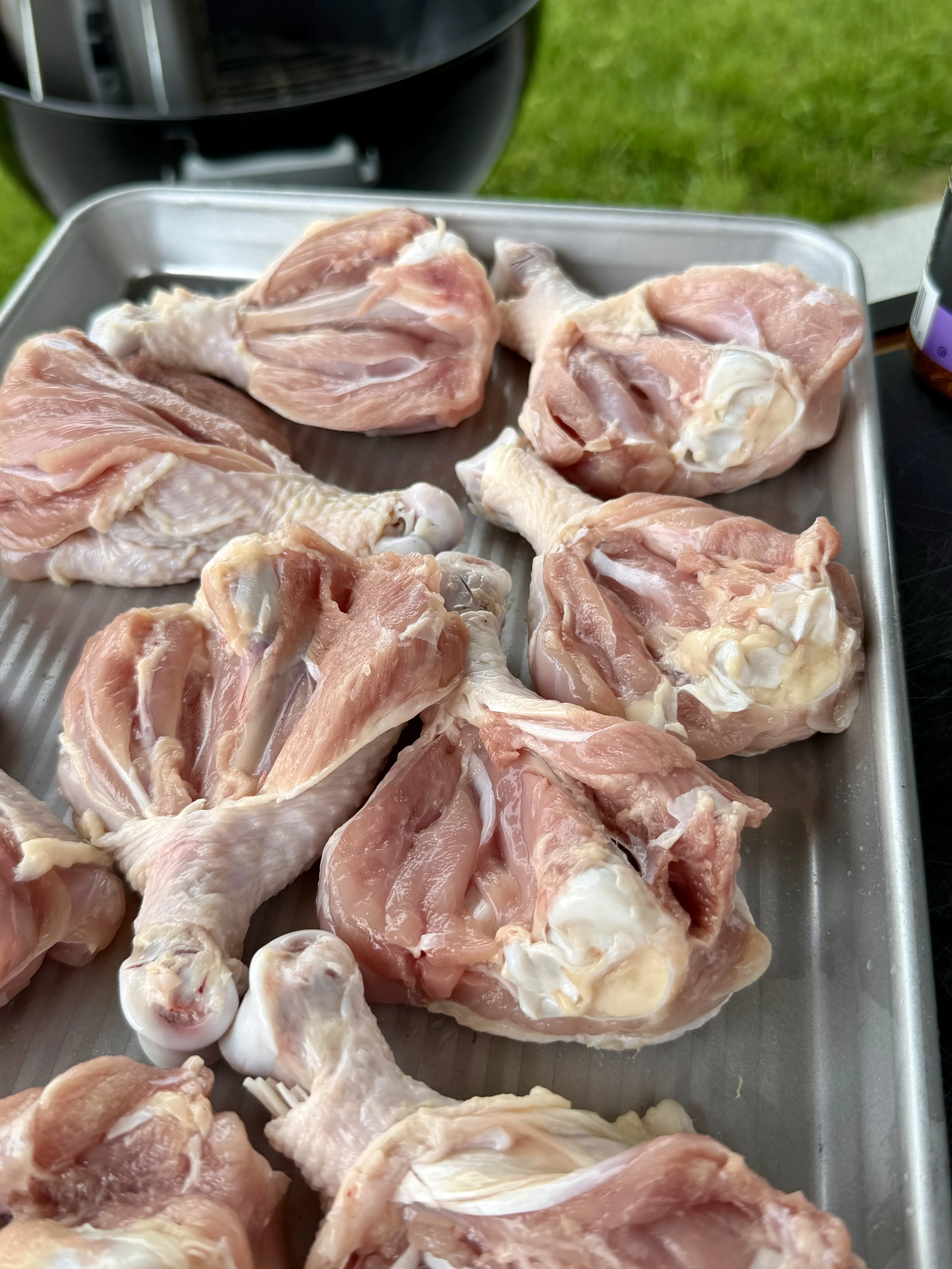 Raw chicken drumsticks arranged on a metal sheet pan, ready to be seasoned with Cajun spices for grilling